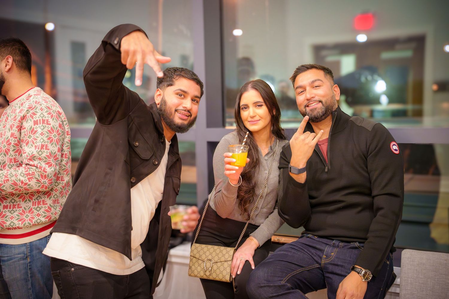 People enjoying drinks and conversation at a social gathering in a modern indoor space.