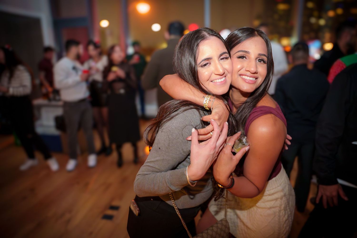 Party attendees sharing laughs and embracing during a festive indoor celebration.