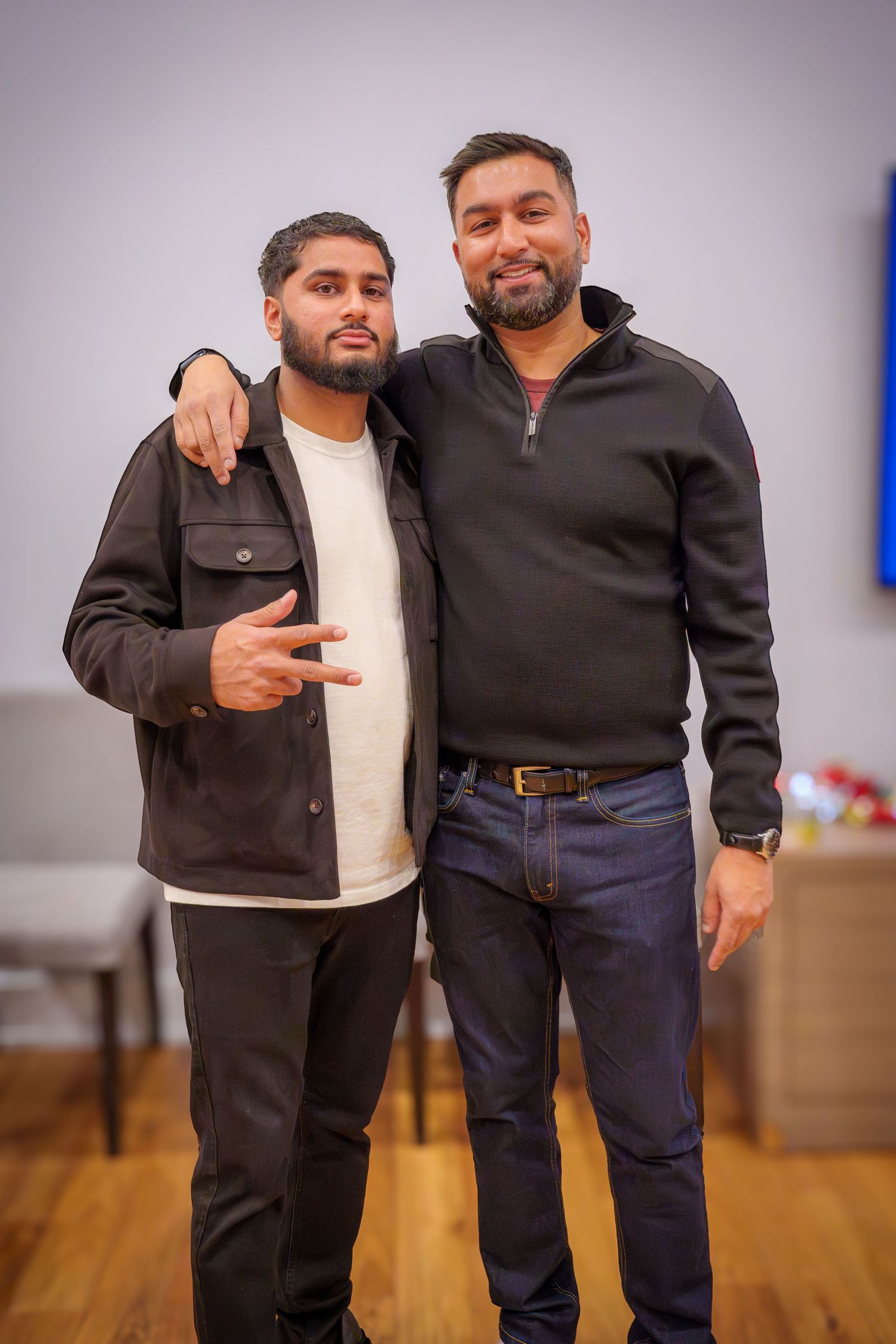 Friends posing together at a casual indoor gathering with wooden floors.