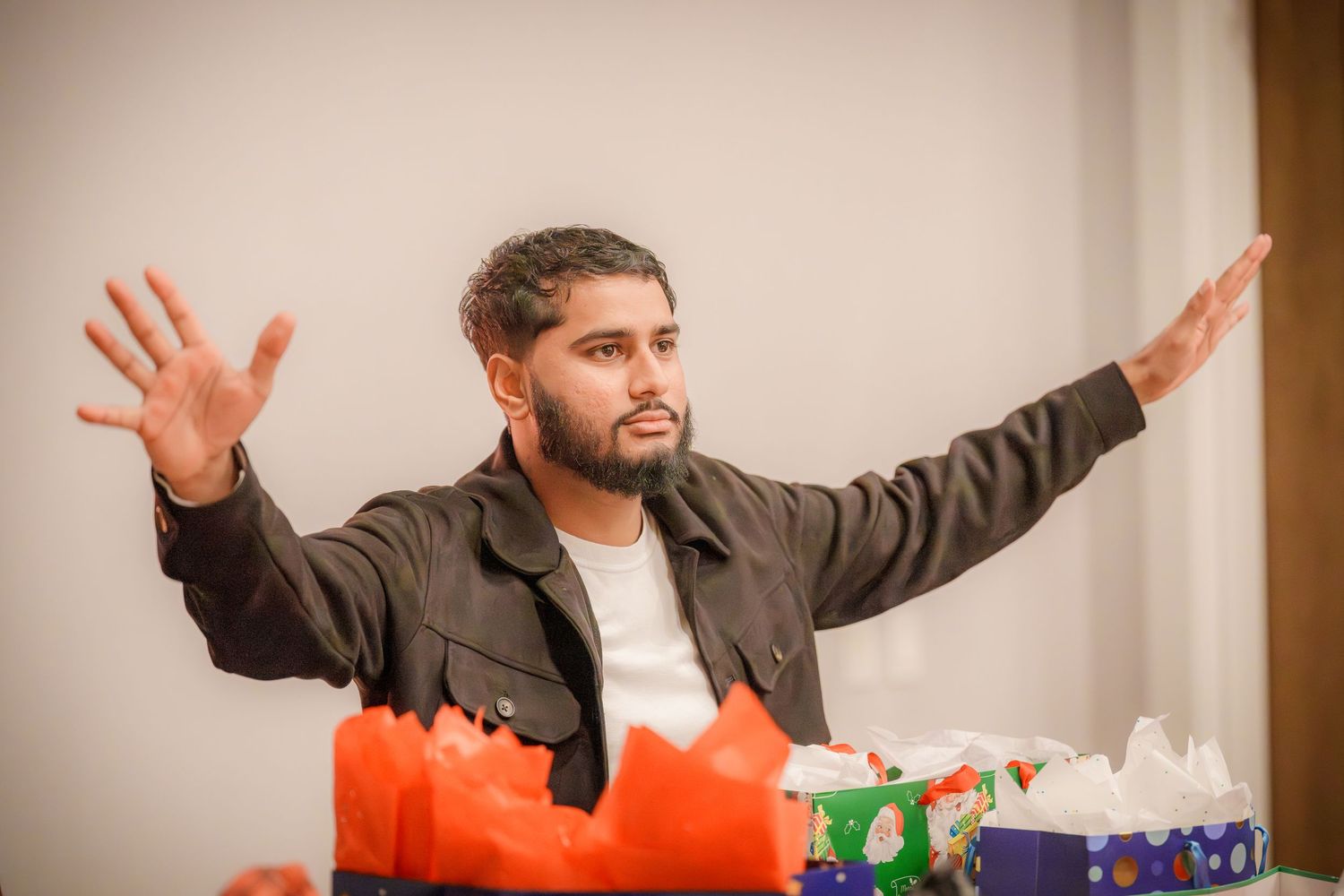 Person gesturing enthusiastically with arms spread wide during an indoor celebration.