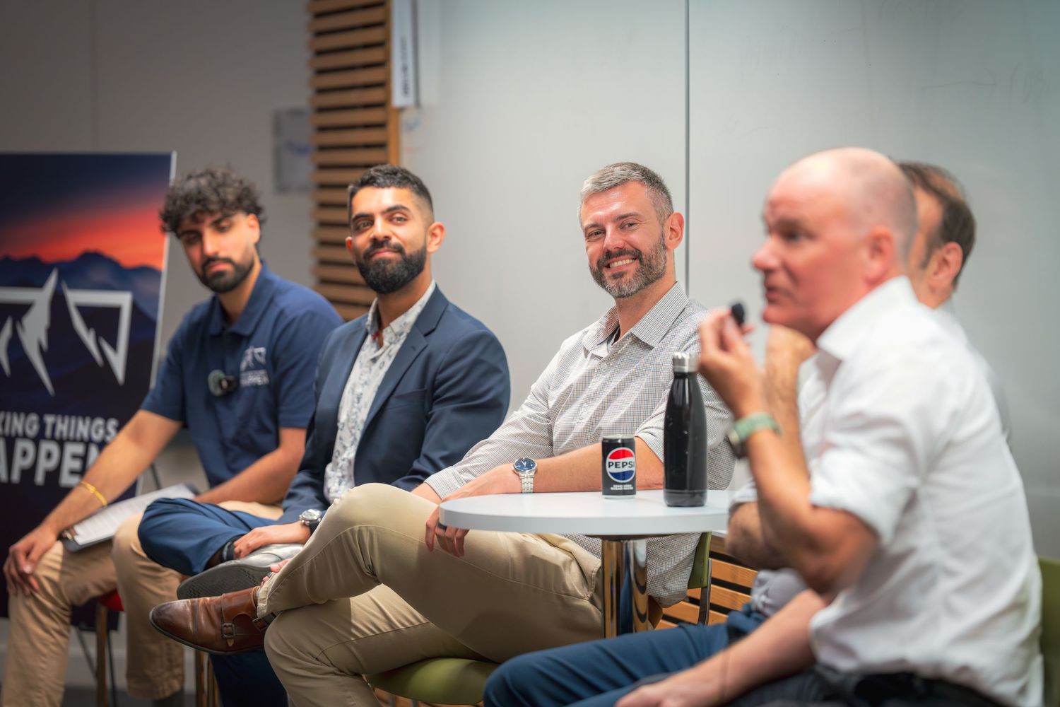 Panel of speakers seated during a professional presentation event.