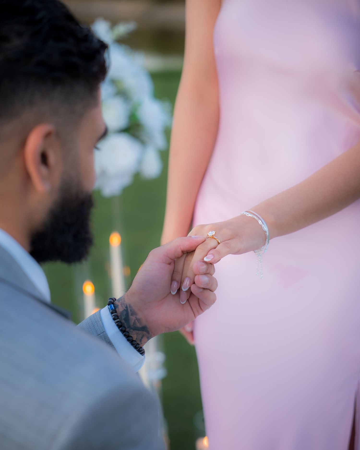Intimate moment showing hands and engagement ring during sunset proposal.
