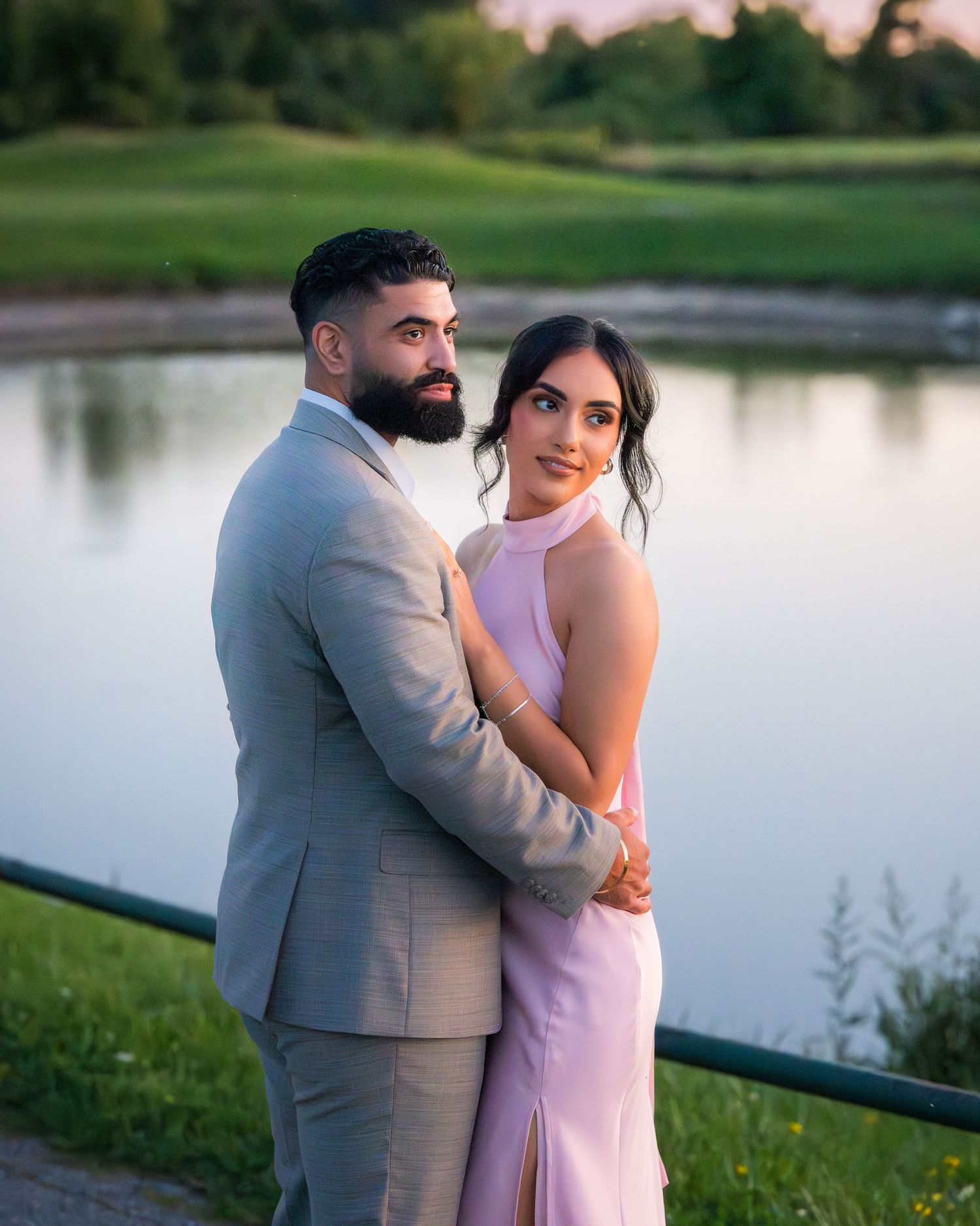 Sweet moment between couple in formal wear against peaceful lake setting.