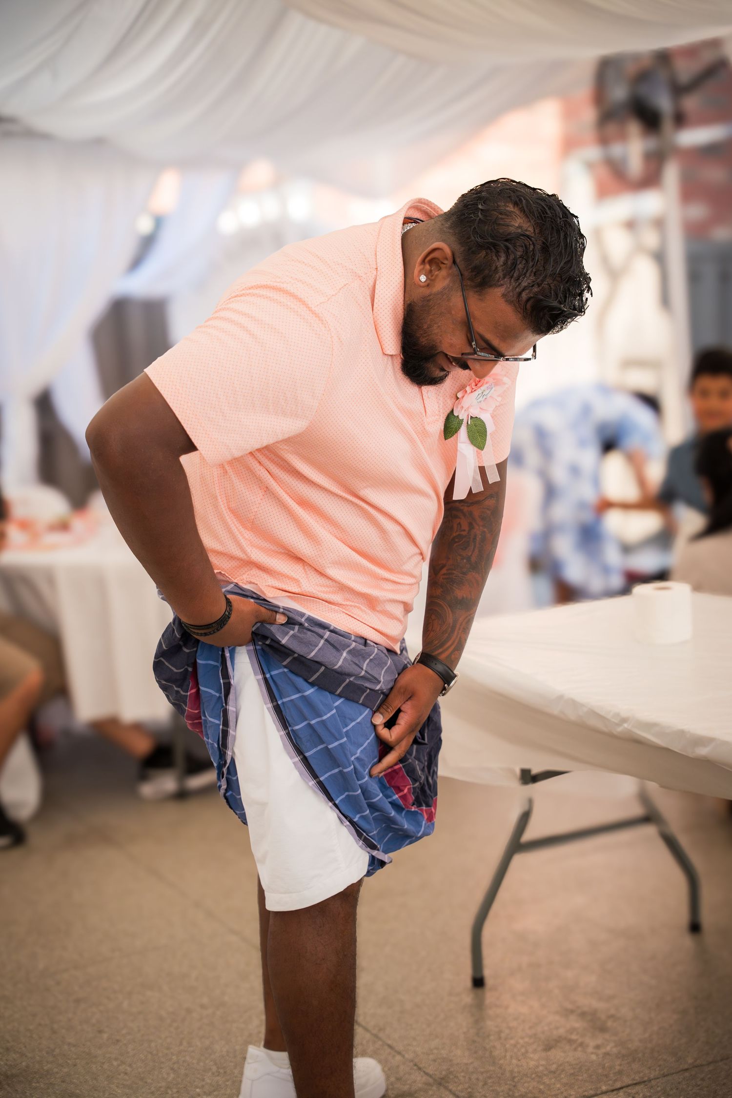 Person in casual summer attire adjusting their clothing at an indoor gathering.
