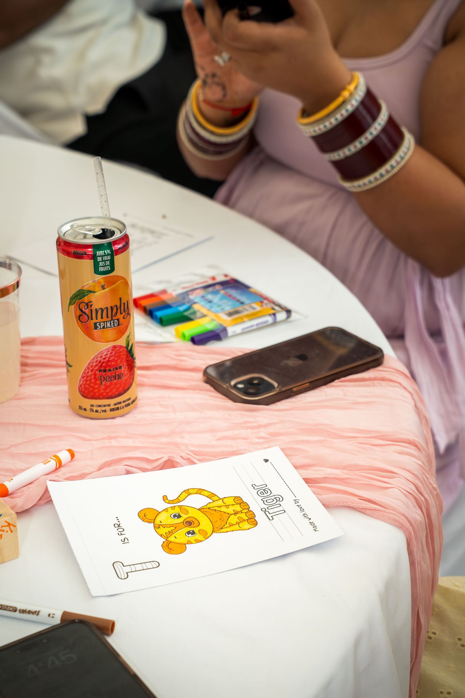 Table setting with colorful drinks, phone, and unicorn coloring page.