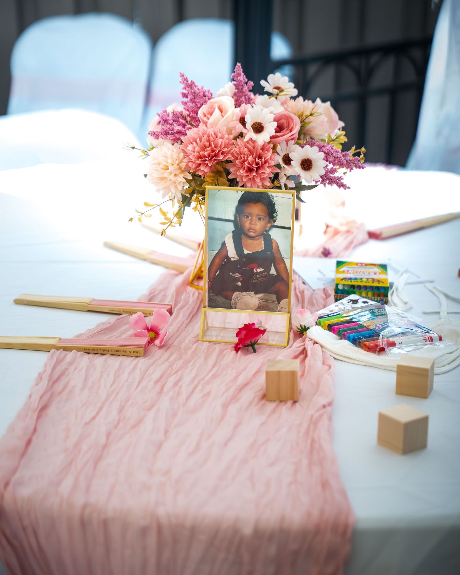 Pink table runner with floral arrangements and decorative elements for celebration setup.