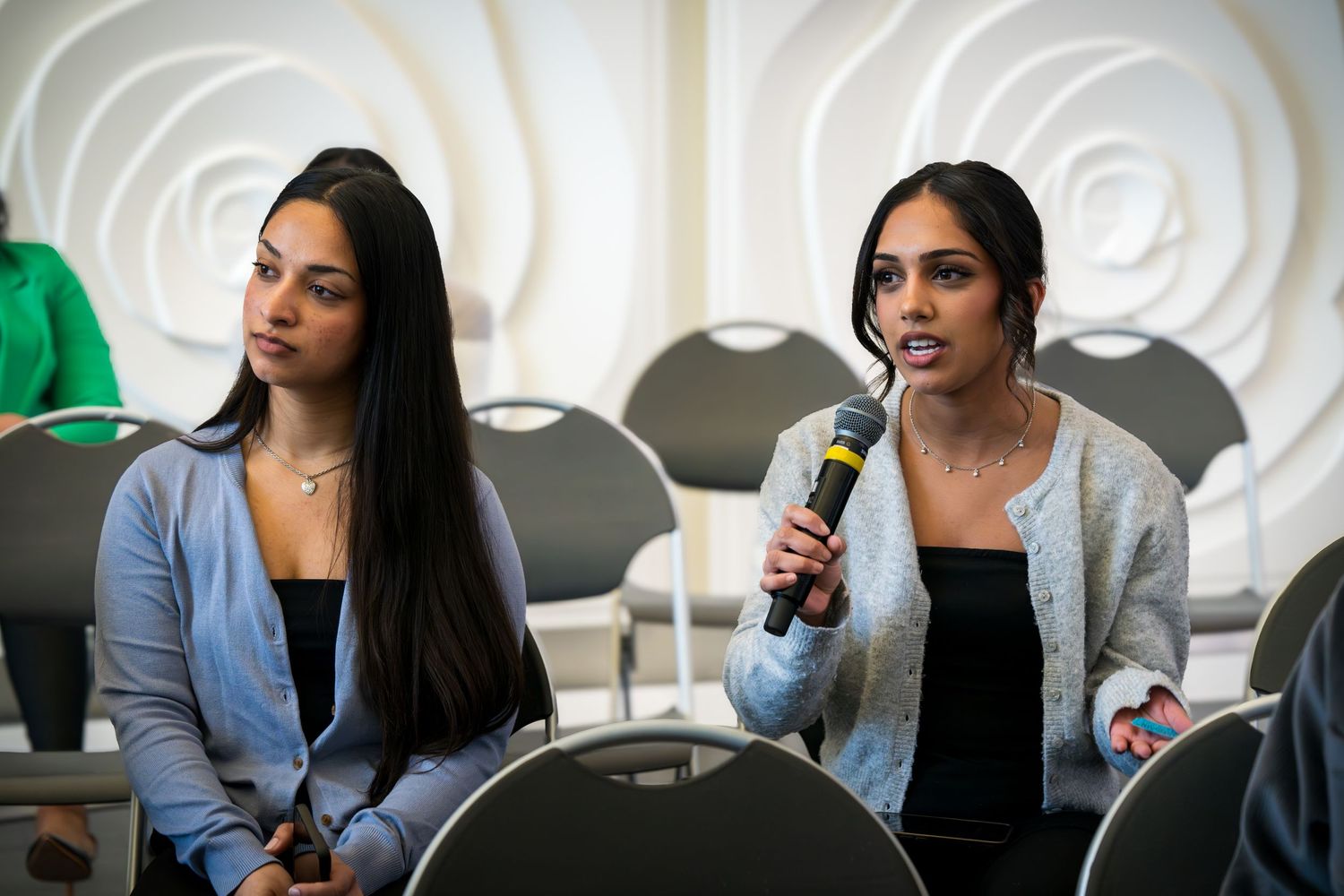 Panelists participate in a professional discussion against a white geometric wall backdrop.