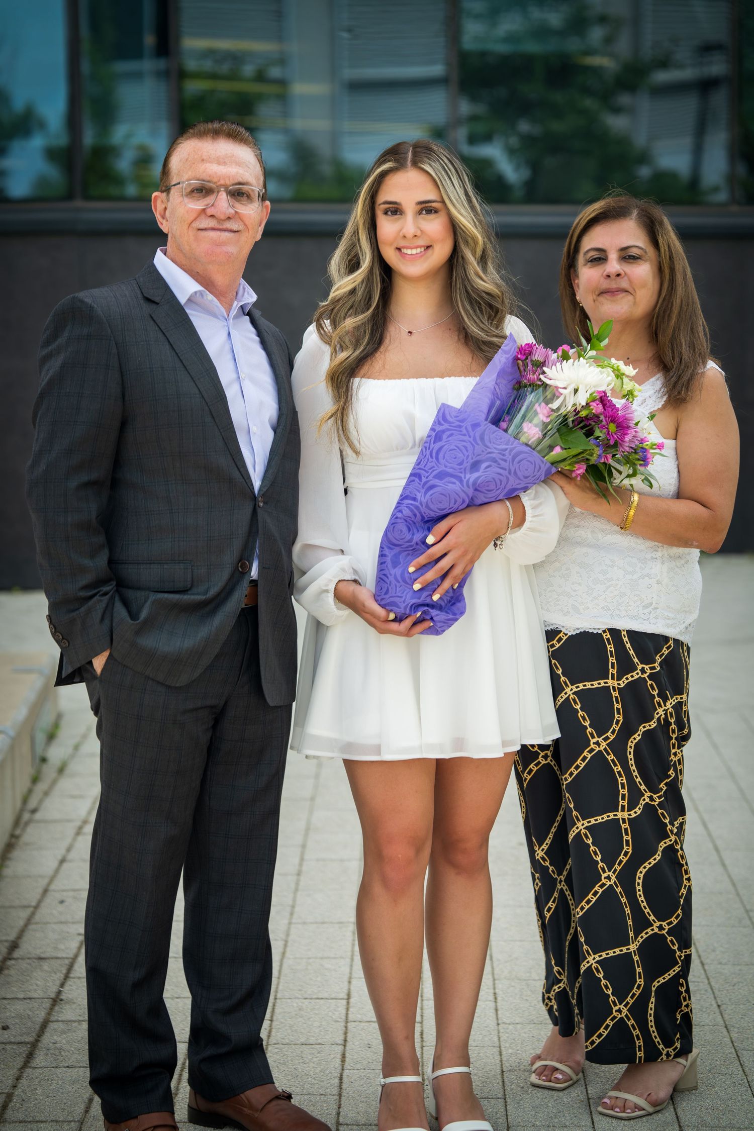 Group portrait with people in formal and casual attire standing on stone pavement.