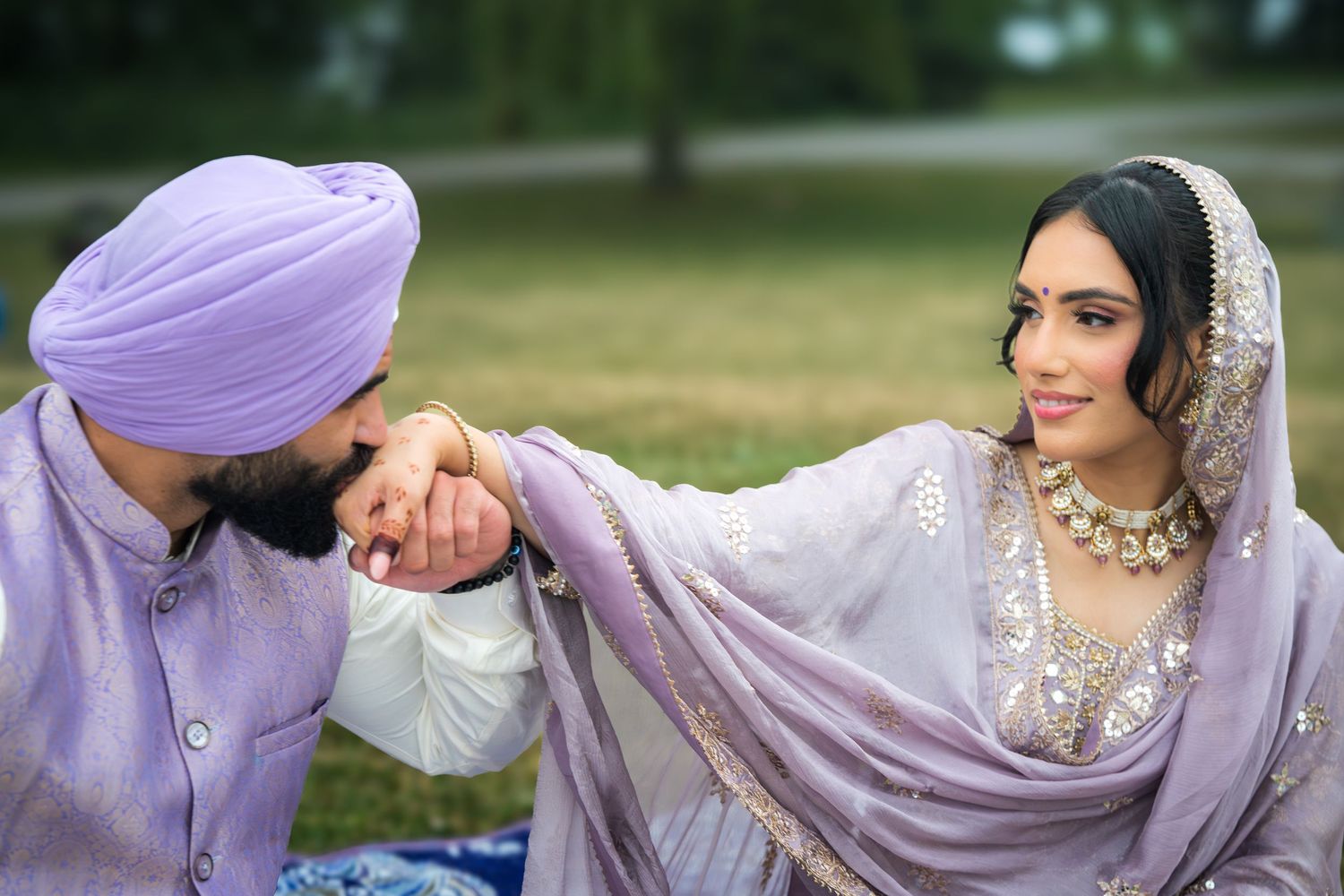 Romantic outdoor photoshoot featuring a couple in coordinating purple and white traditional South Asian attire.