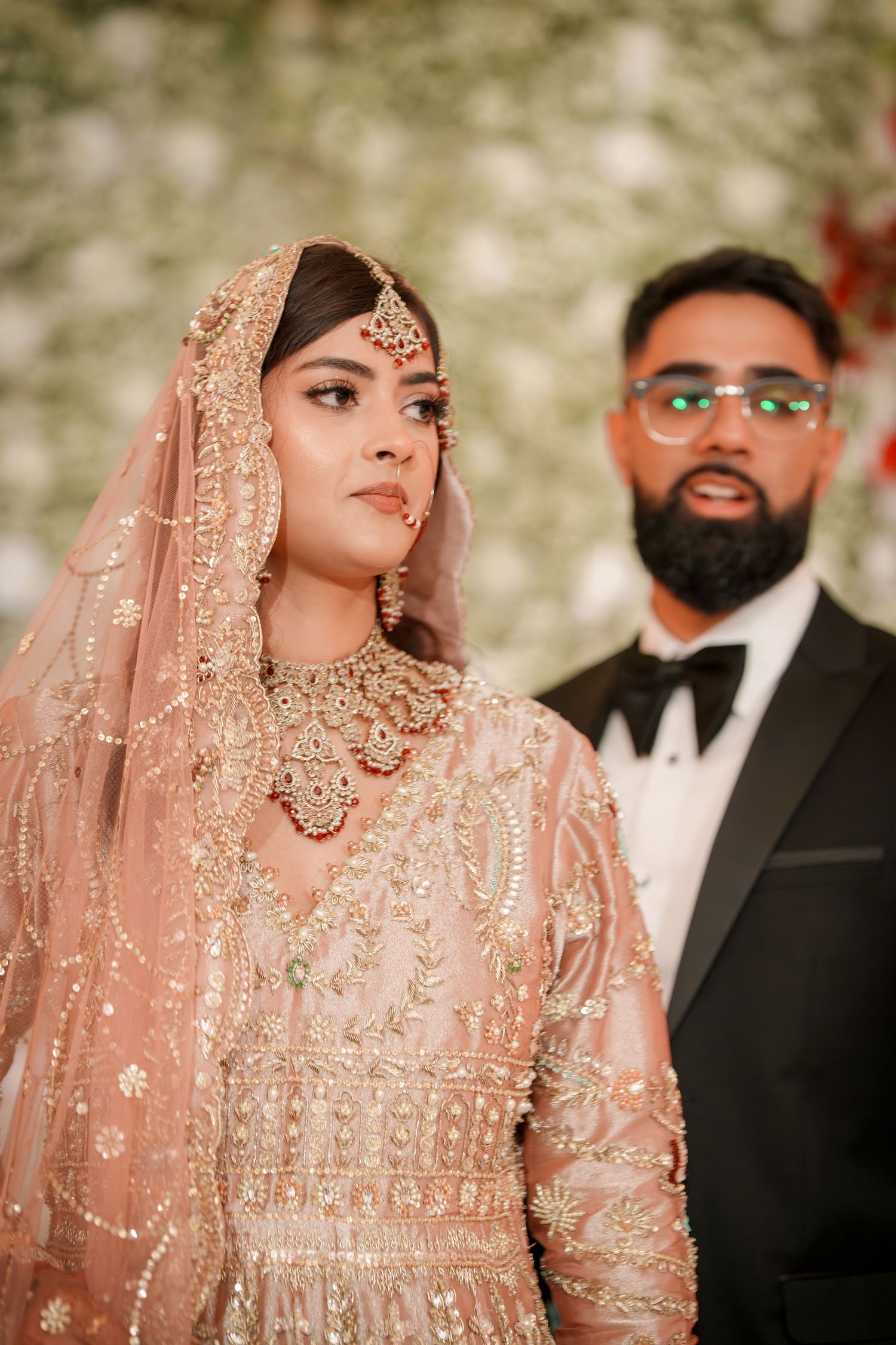 Wedding portraits showing intricate details of bride's peach embroidered outfit and groom's formal attire.