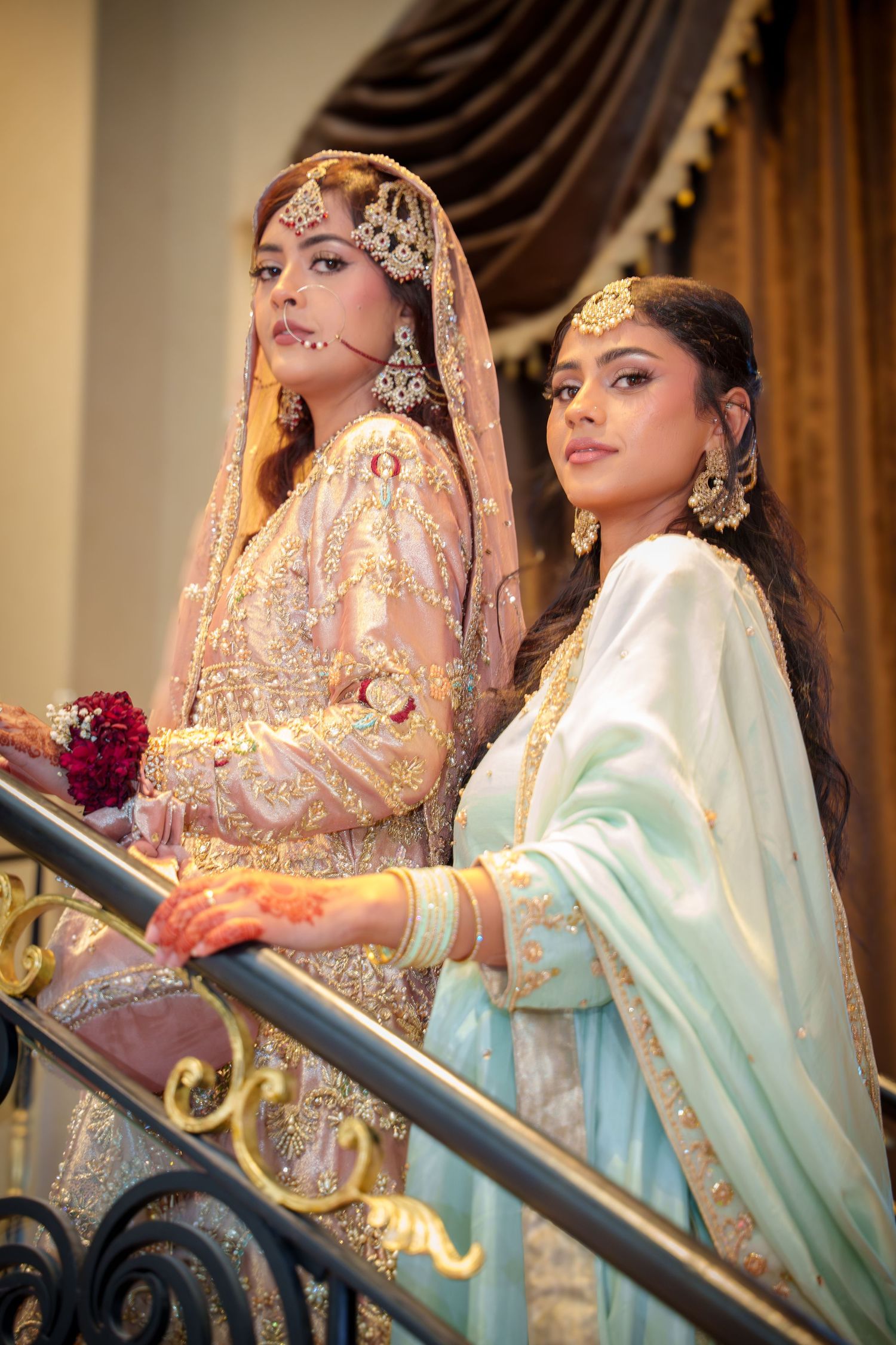 Wedding party members in traditional South Asian attire pose along an elegant staircase.