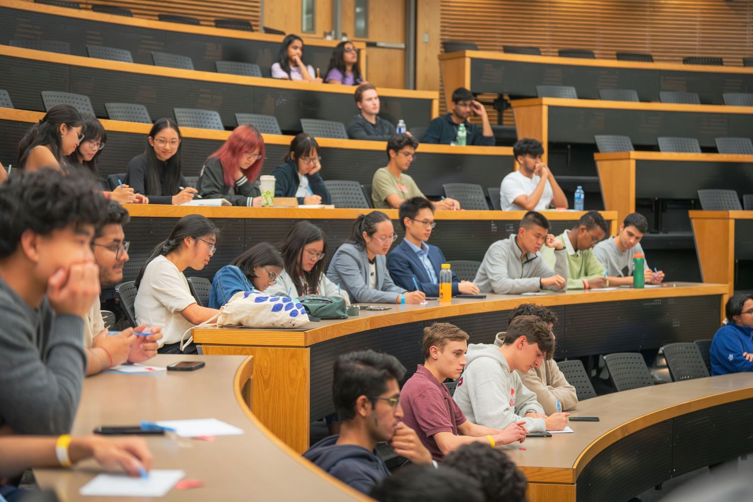 Students attending business presentation in curved amphitheater-style classroom.