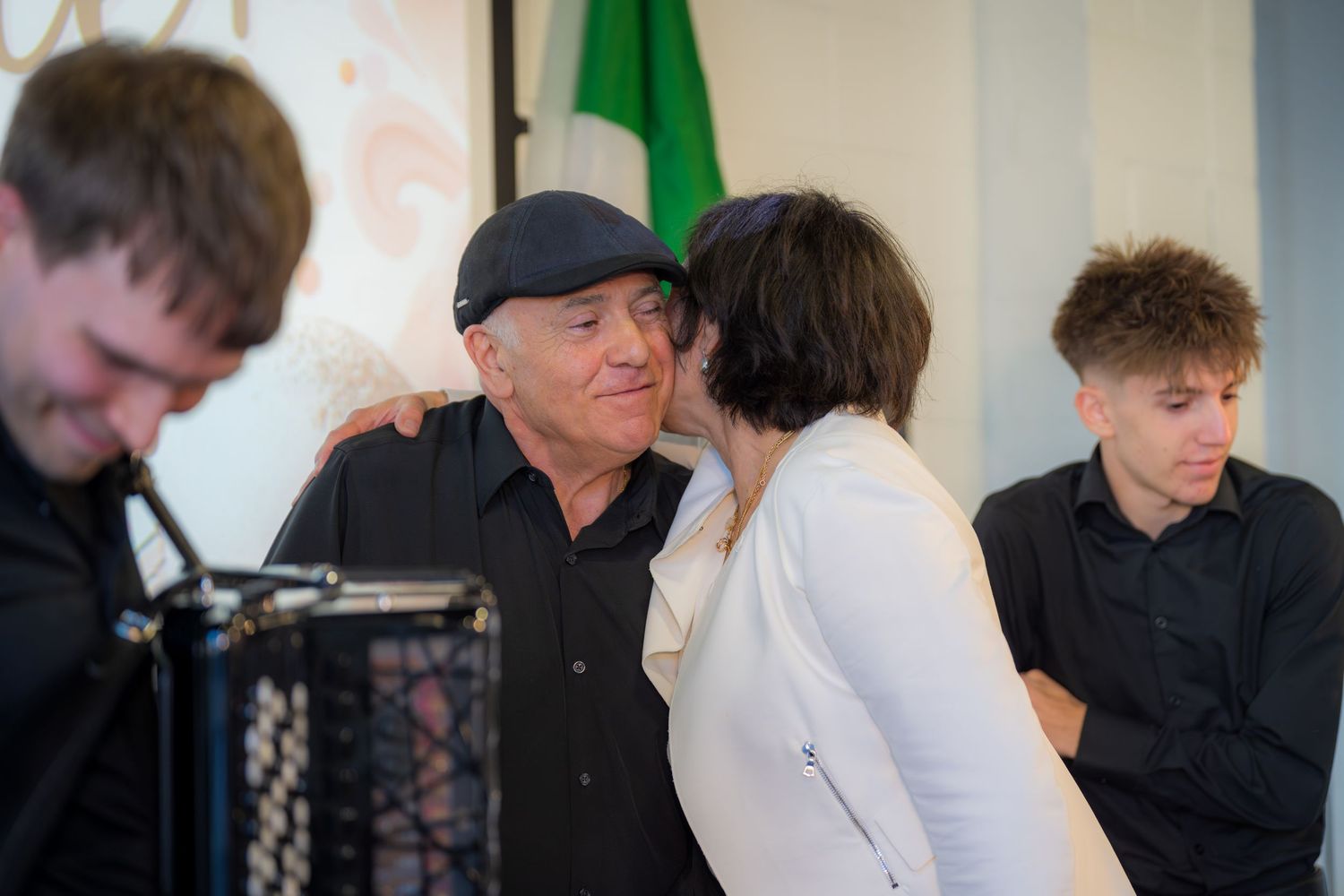 Man in black cap receiving kiss on cheek at music event.