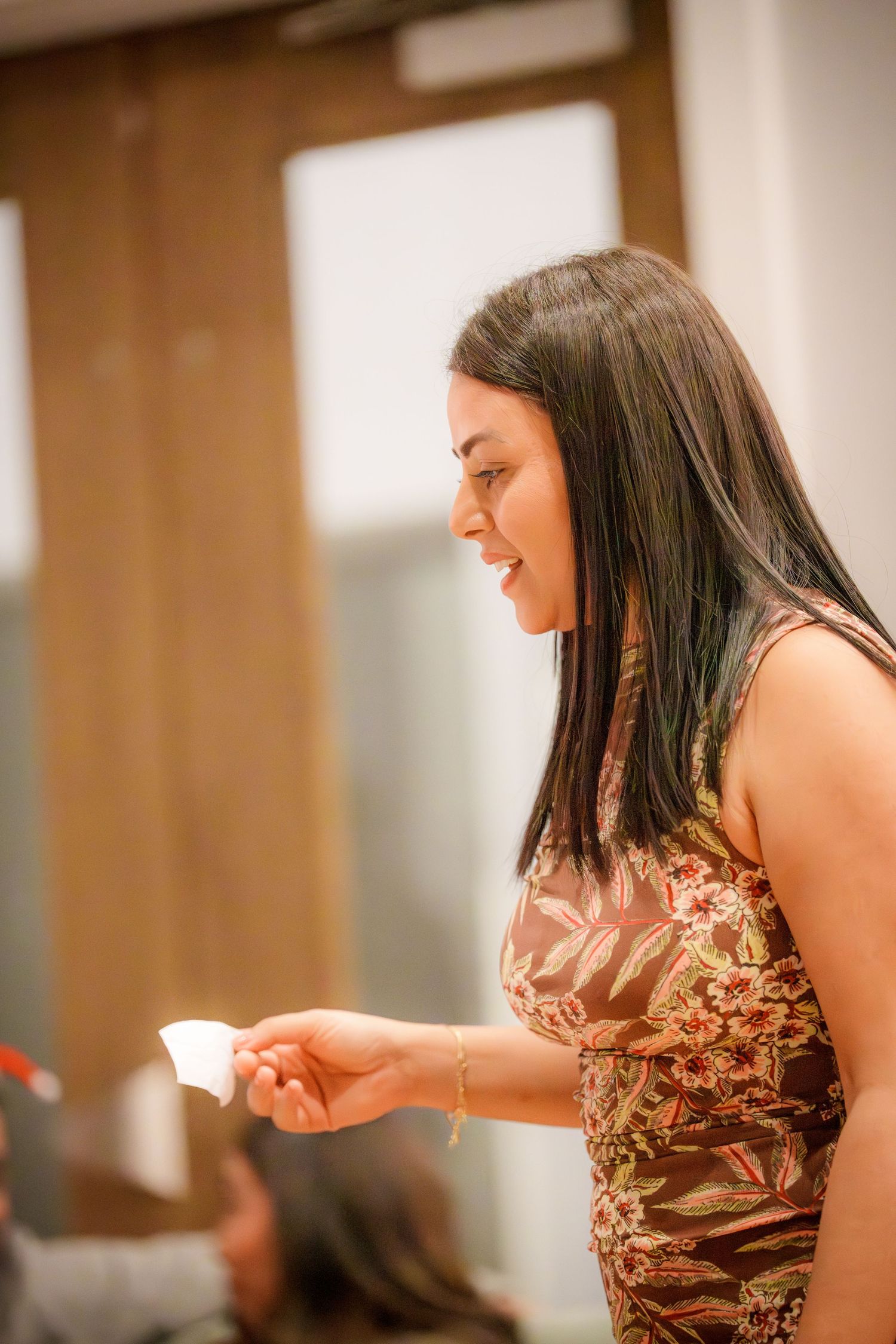 Woman in a shimmering dress gestures animatedly during a social gathering.