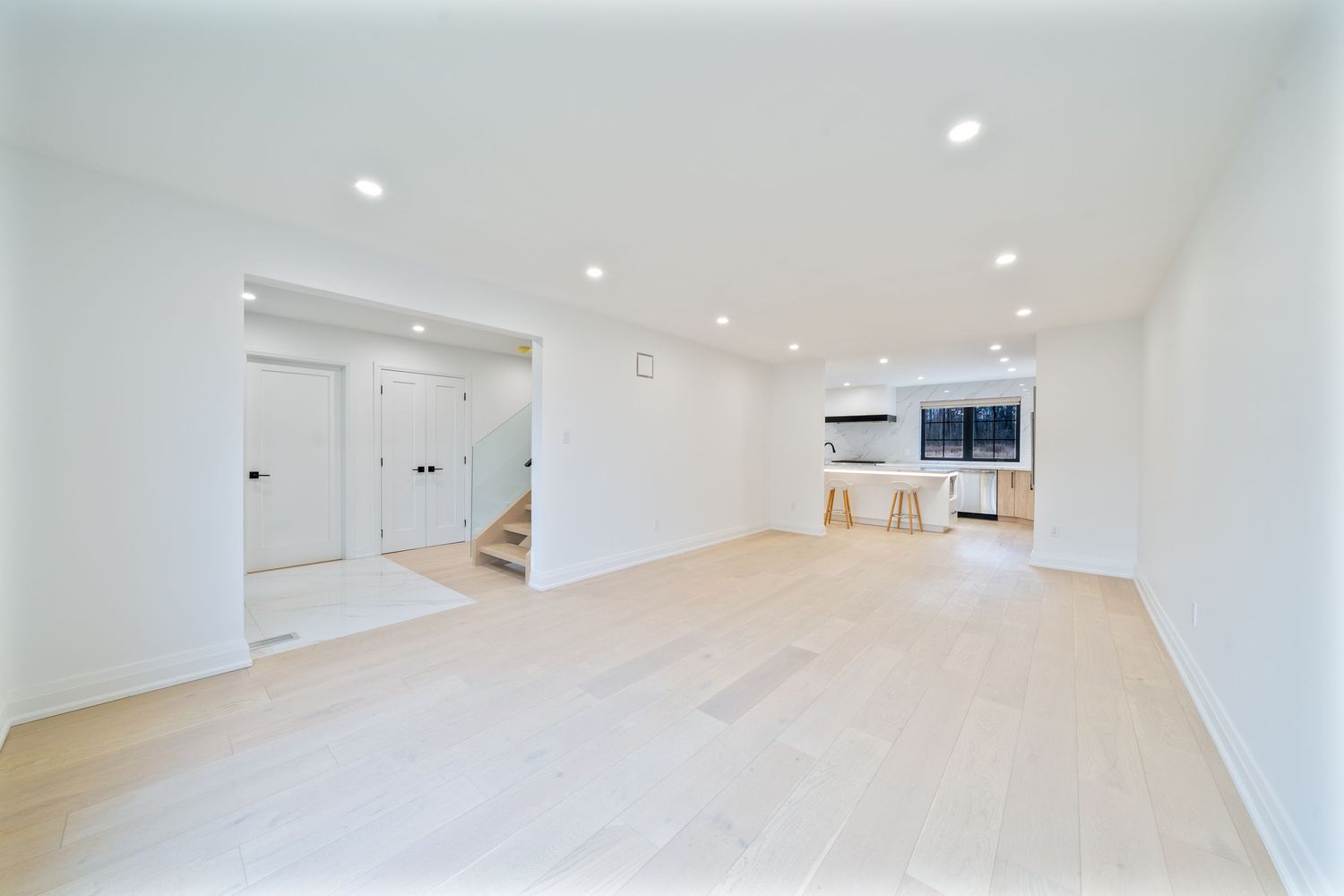 Modern white room interior with light wood flooring and recessed lighting in ceiling creates bright minimal space.