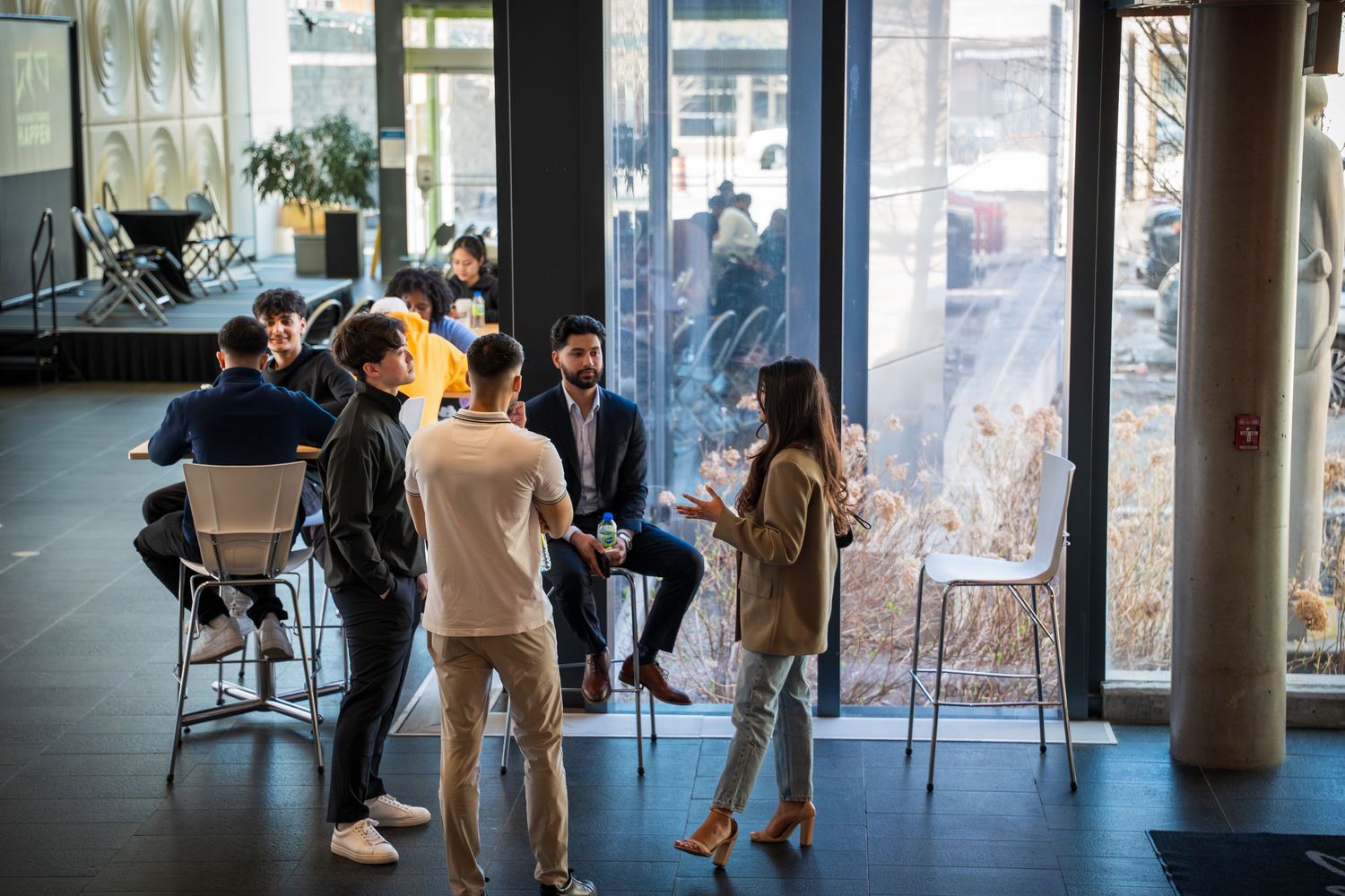People walking through a modern office space with glass walls and natural lighting.