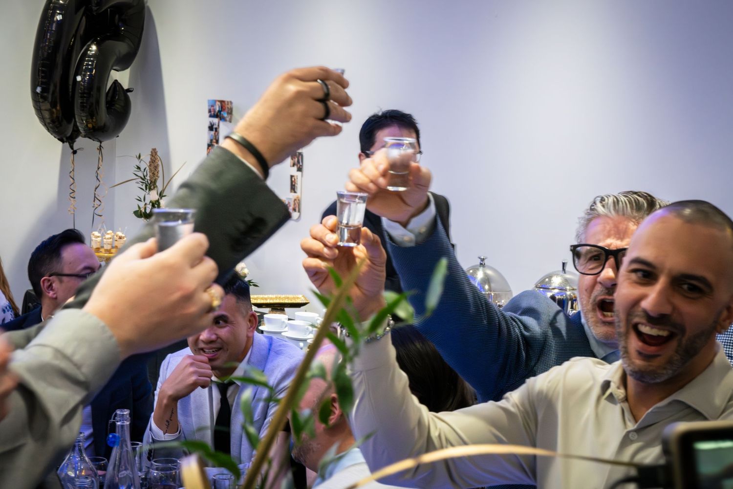 People raising glasses in celebration at an indoor event.