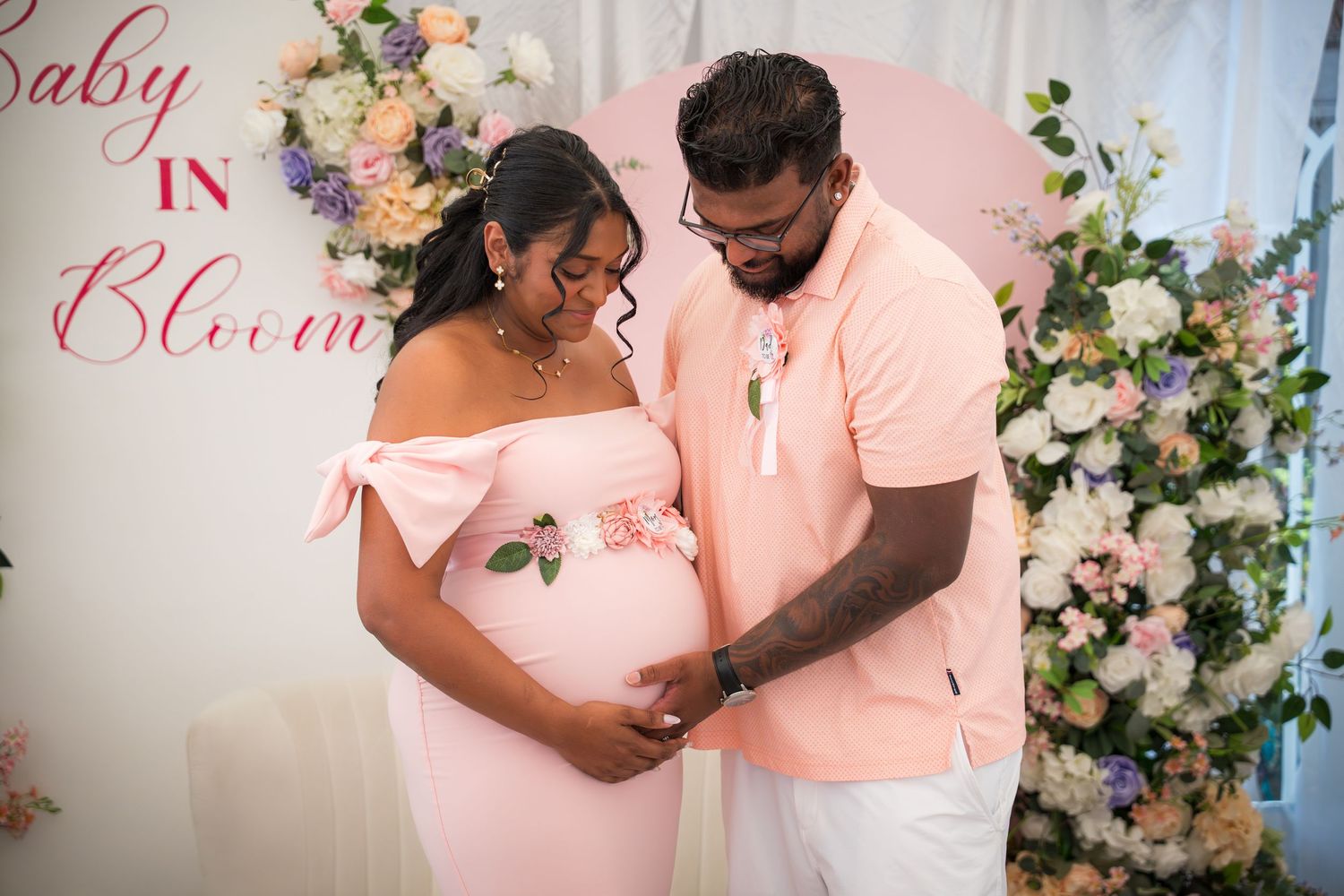 Maternity celebration with pink theme and decorative floral wall display.