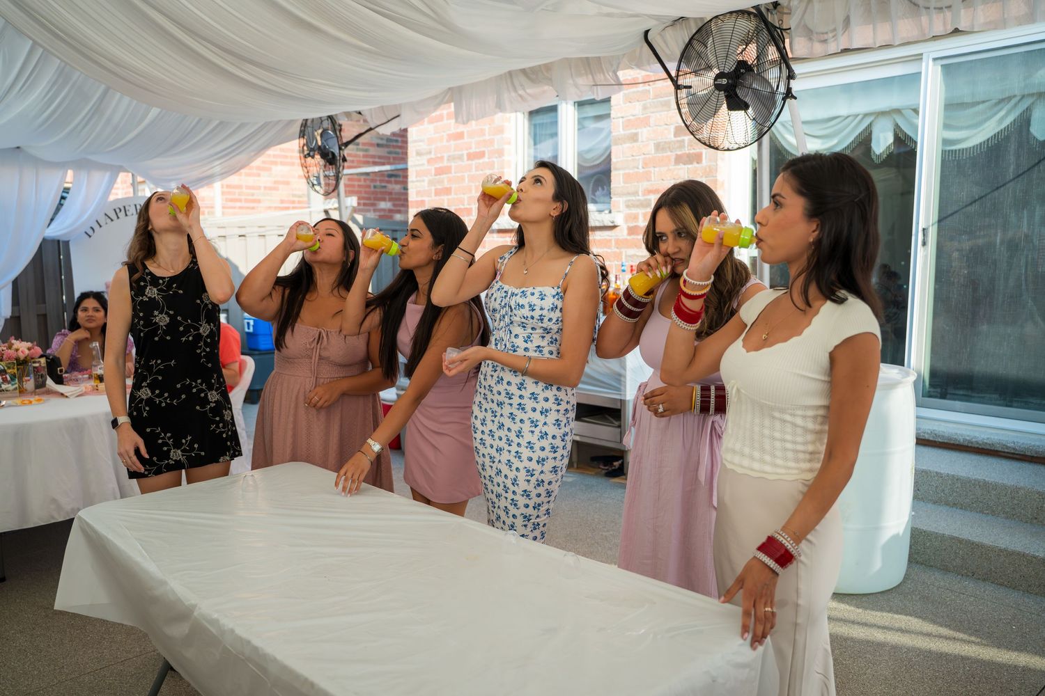 Guests in coordinated attire celebrate at an indoor event with exposed brick walls.