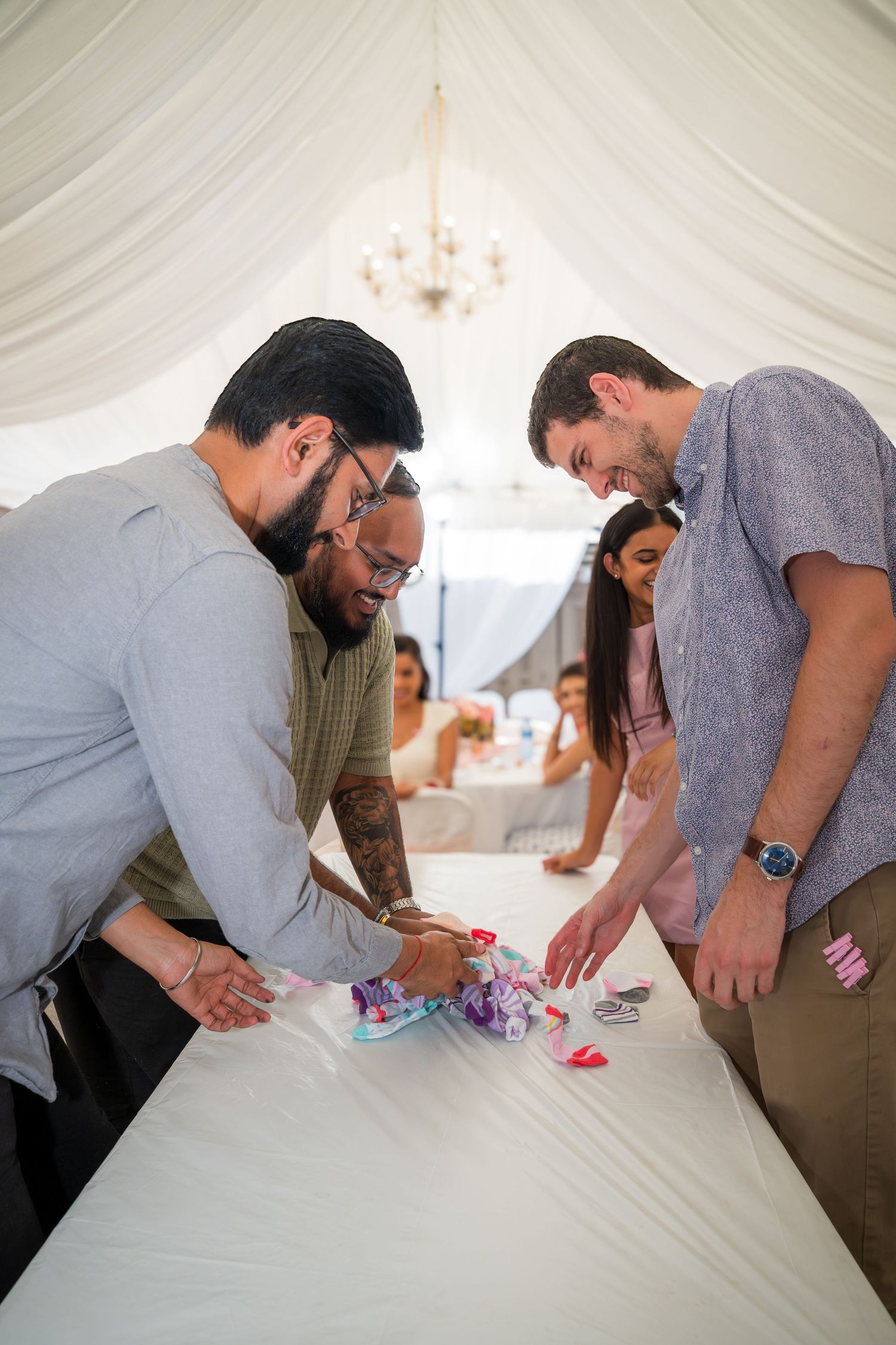 Group working together to set up decorations on a long white table in a wedding tent.