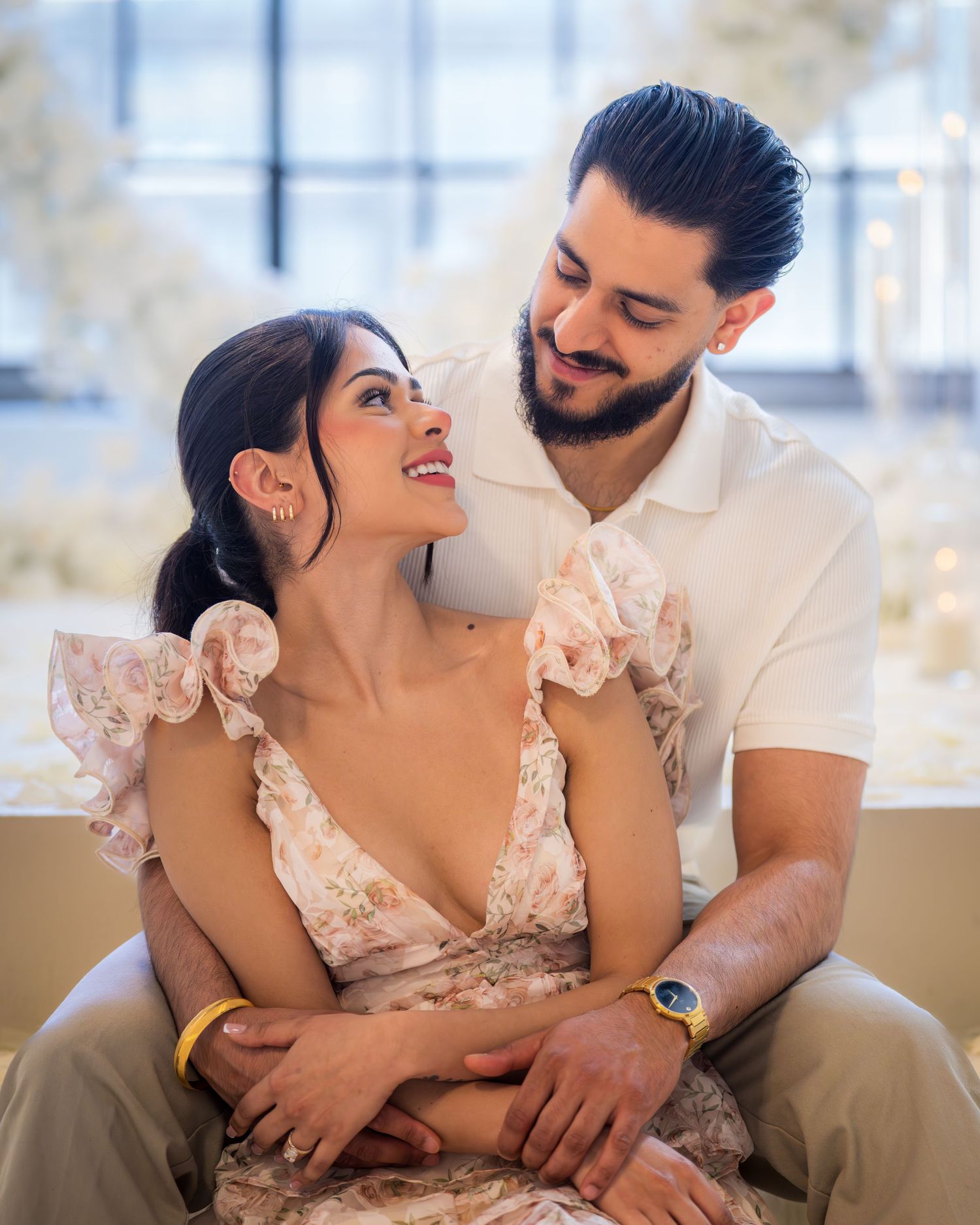 Couple sitting together gazing lovingly at each other with white floral decor.