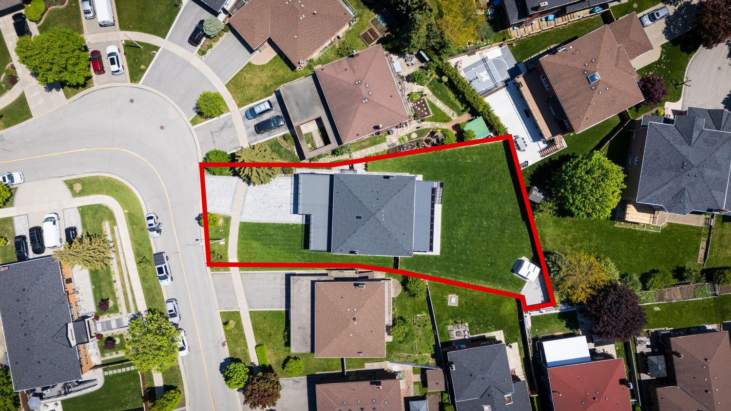 Aerial drone view of residential neighborhood with red property boundary line outlining a single house and yard.