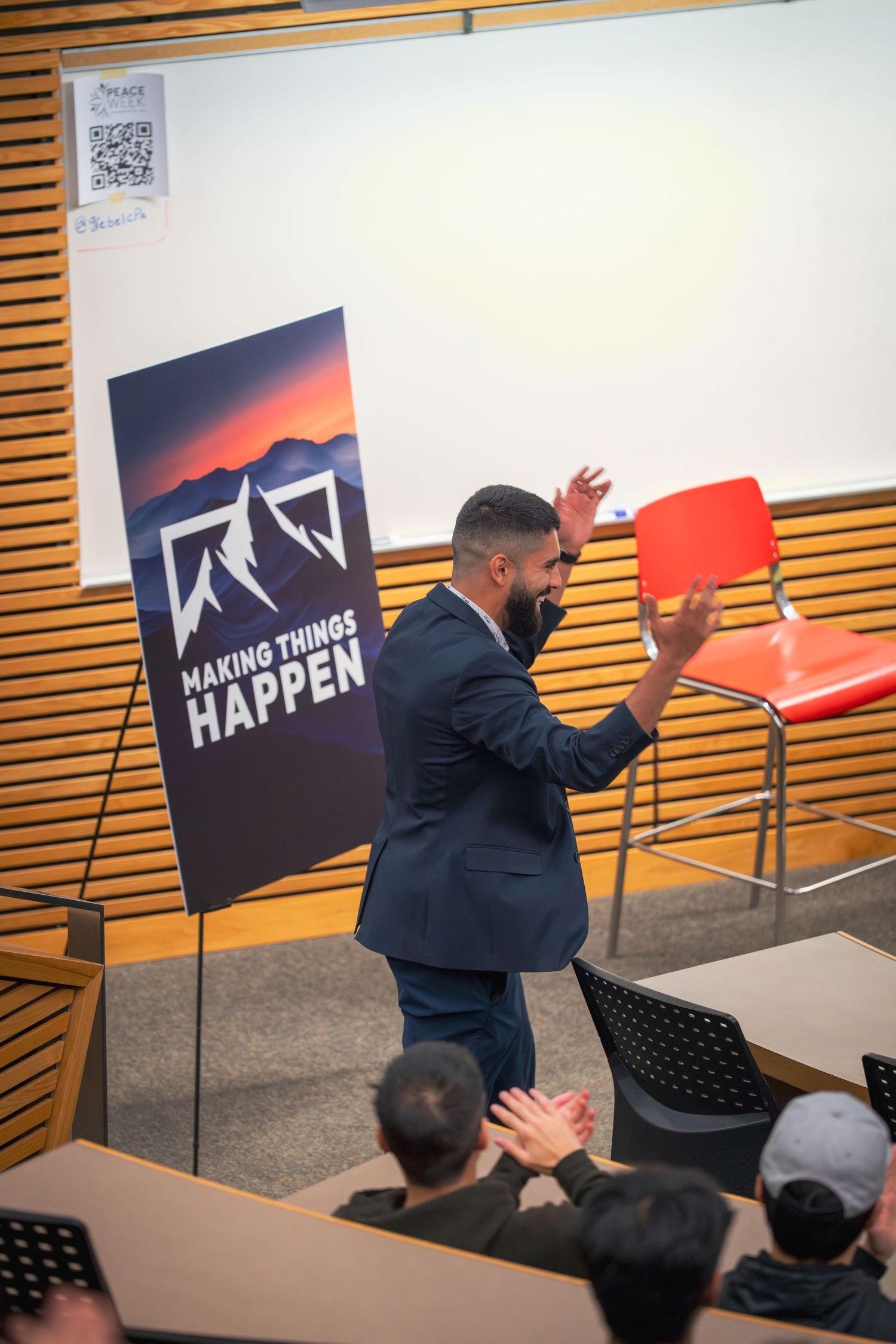 Animated presenter gestures energetically in front of mountain logo backdrop during presentation.