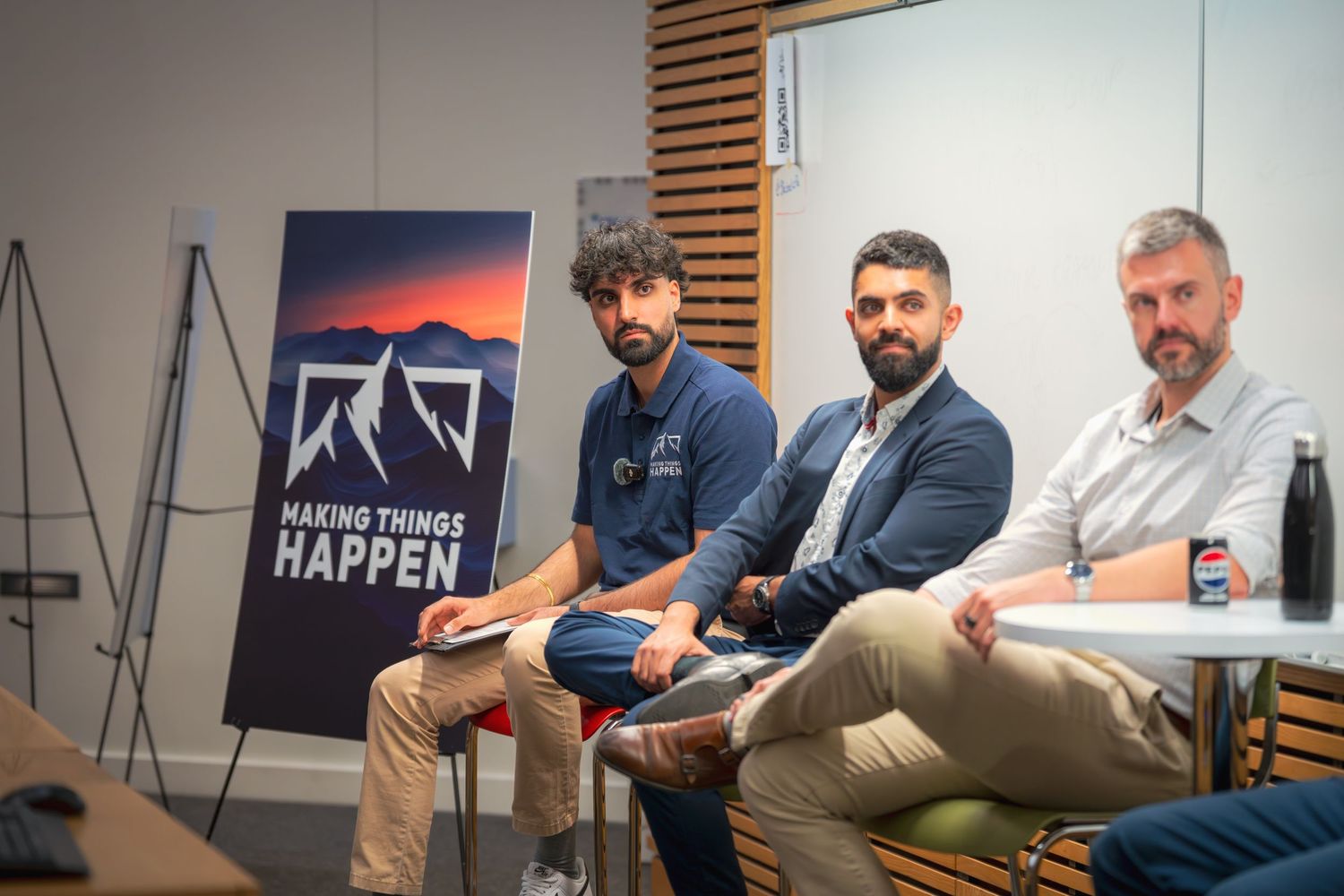 Conference room setting with motivational wall art and wooden panel backdrop during a business meeting.