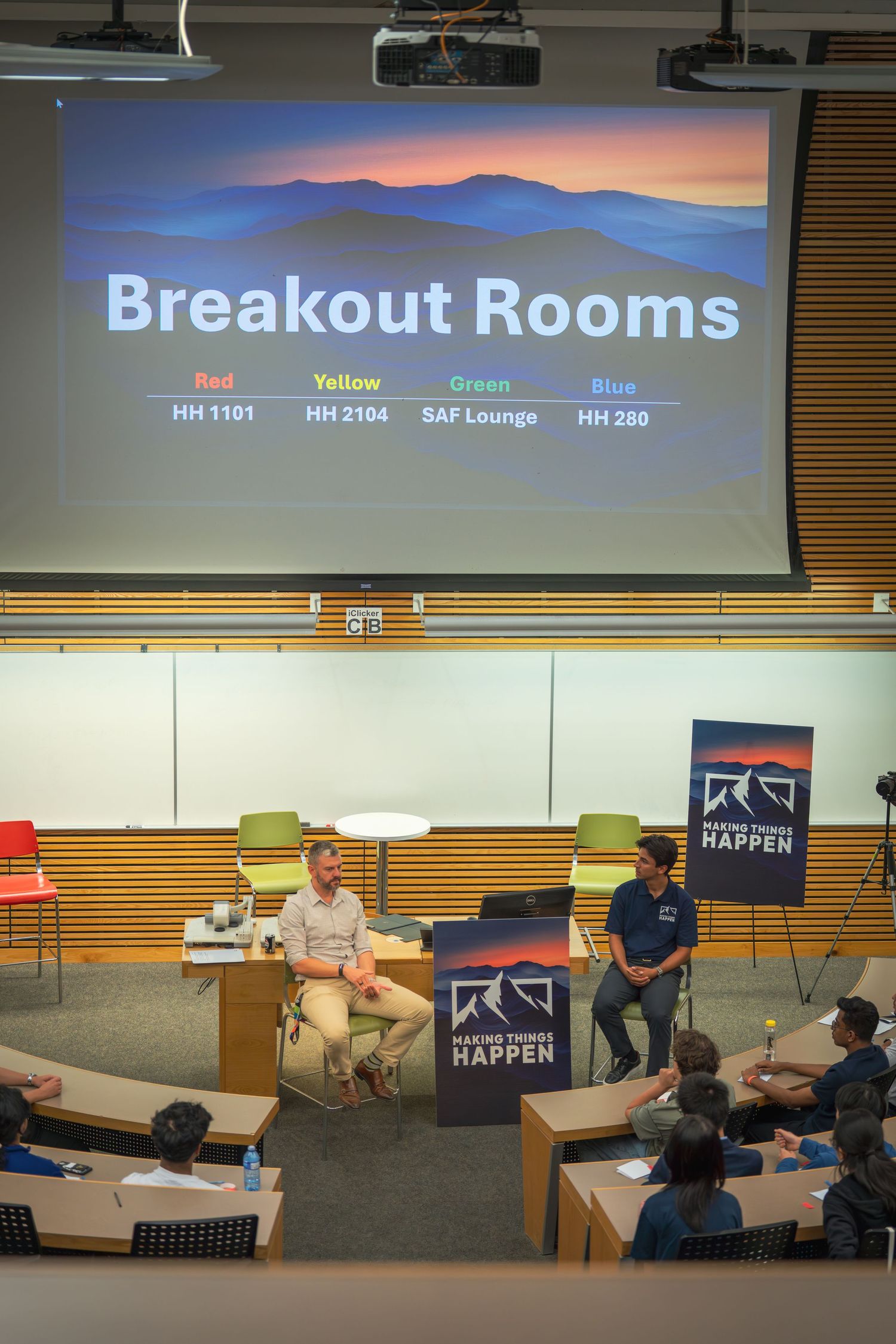 Conference room with breakout session information displayed on projector screen.