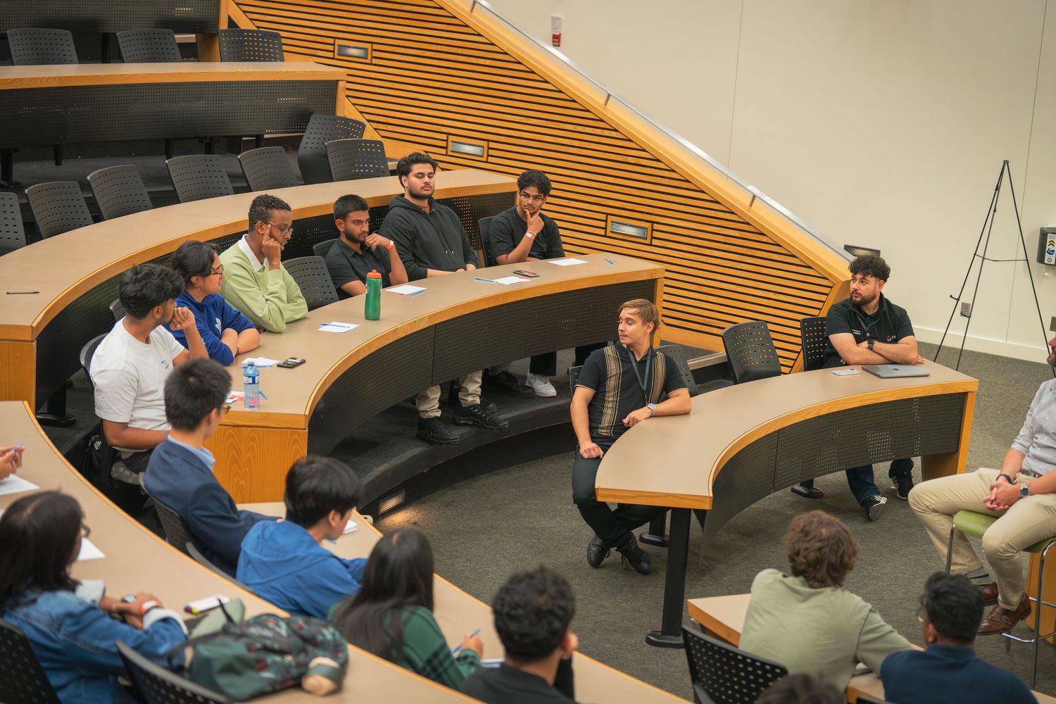 Wide view of conference attendees seated in curved rows during a presentation session.