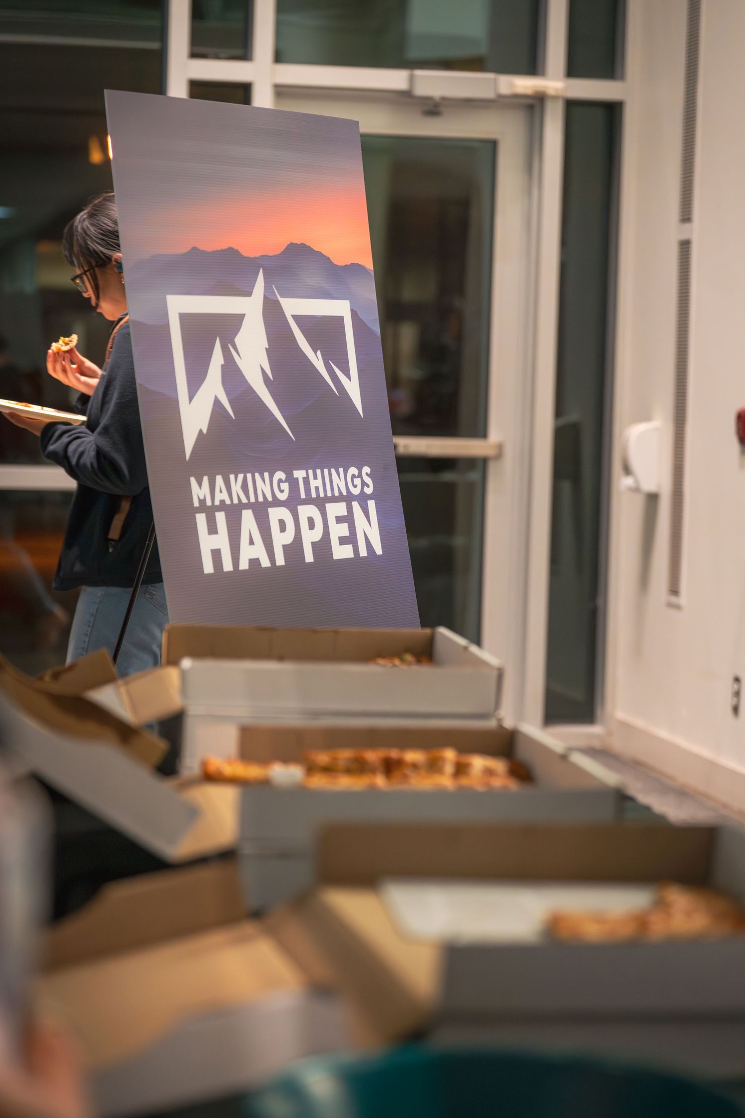 Marketing banner with mountain logo and 'Making Things Happen' text displayed near pizza boxes.