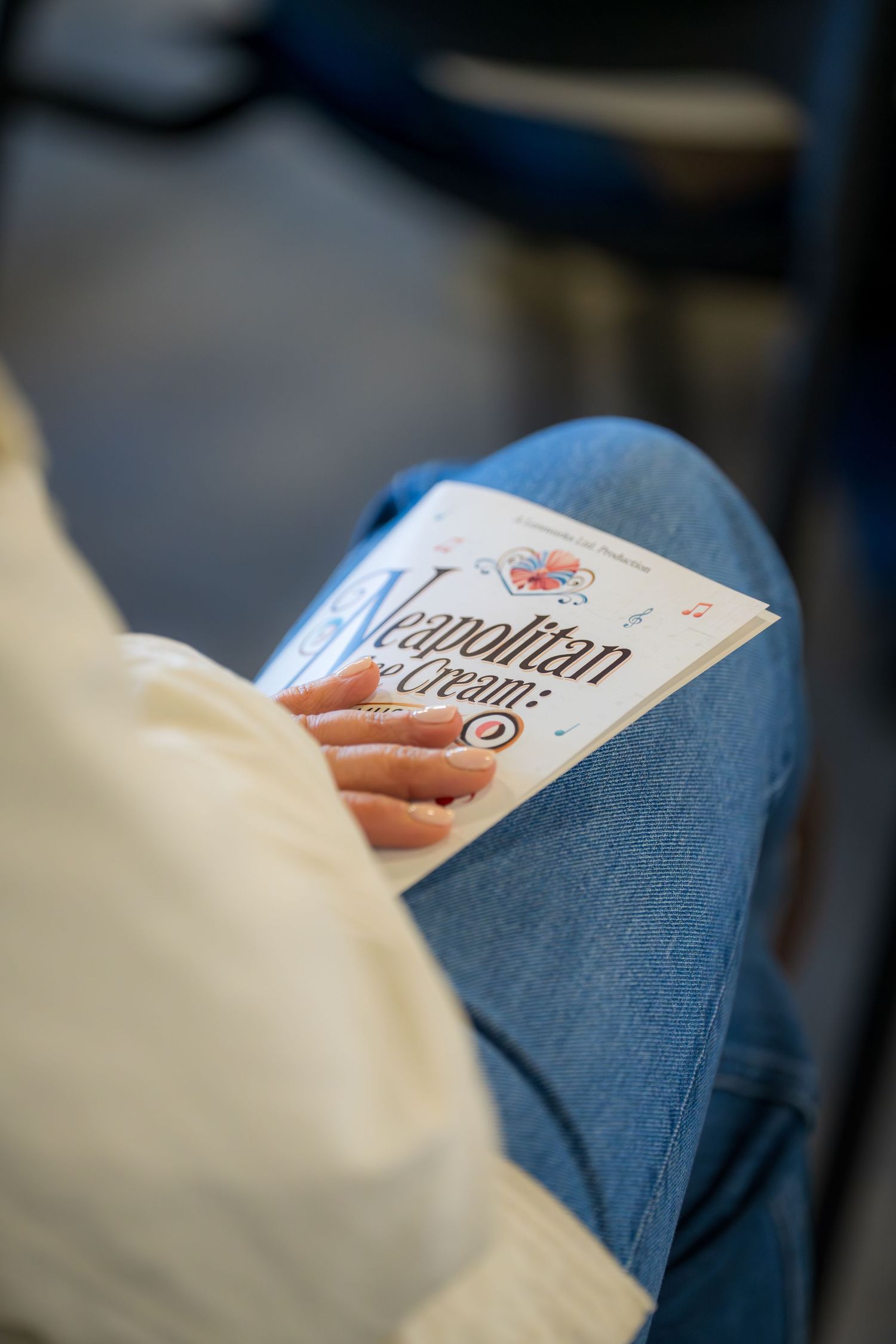 Audience member holds Neapolitan Ice Cream musical program booklet while seated at live show.