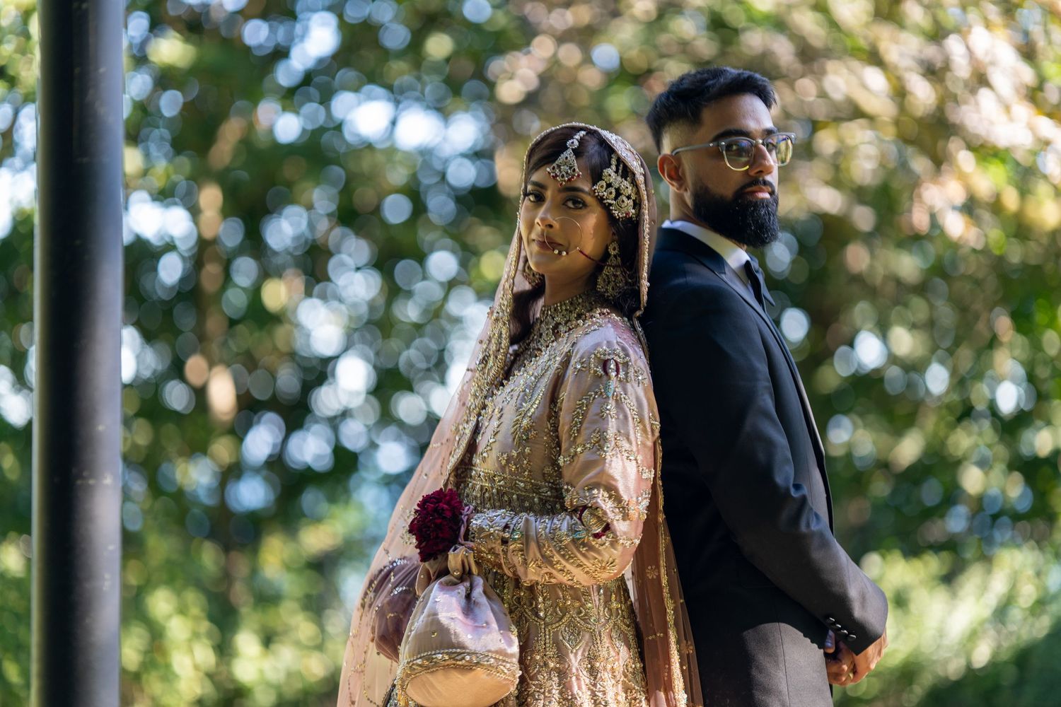Elegant wedding portrait session in outdoor garden with couple in traditional South Asian formal wear.