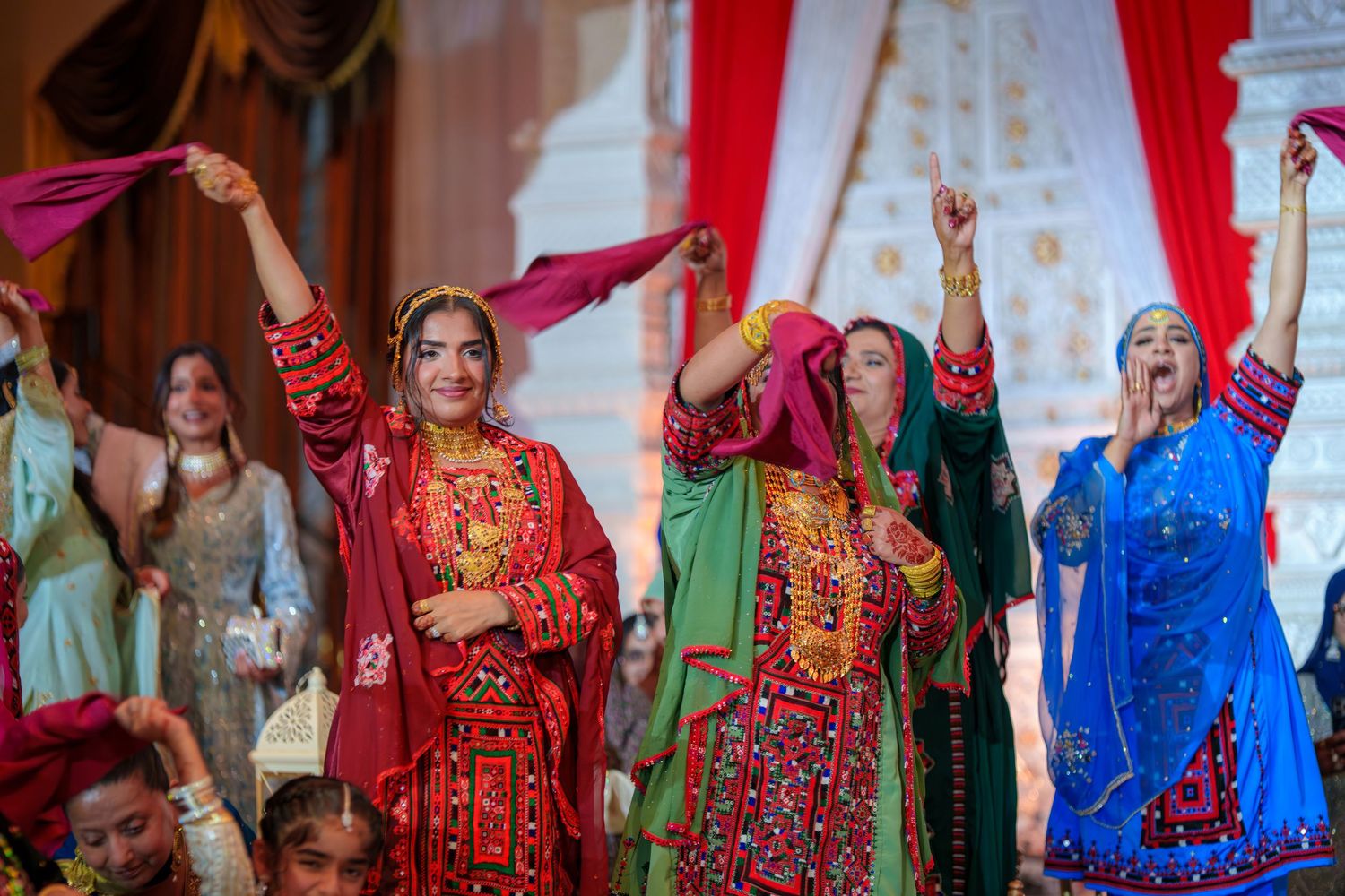 Festive wedding celebration with guests in colorful traditional South Asian outfits dancing and celebrating.