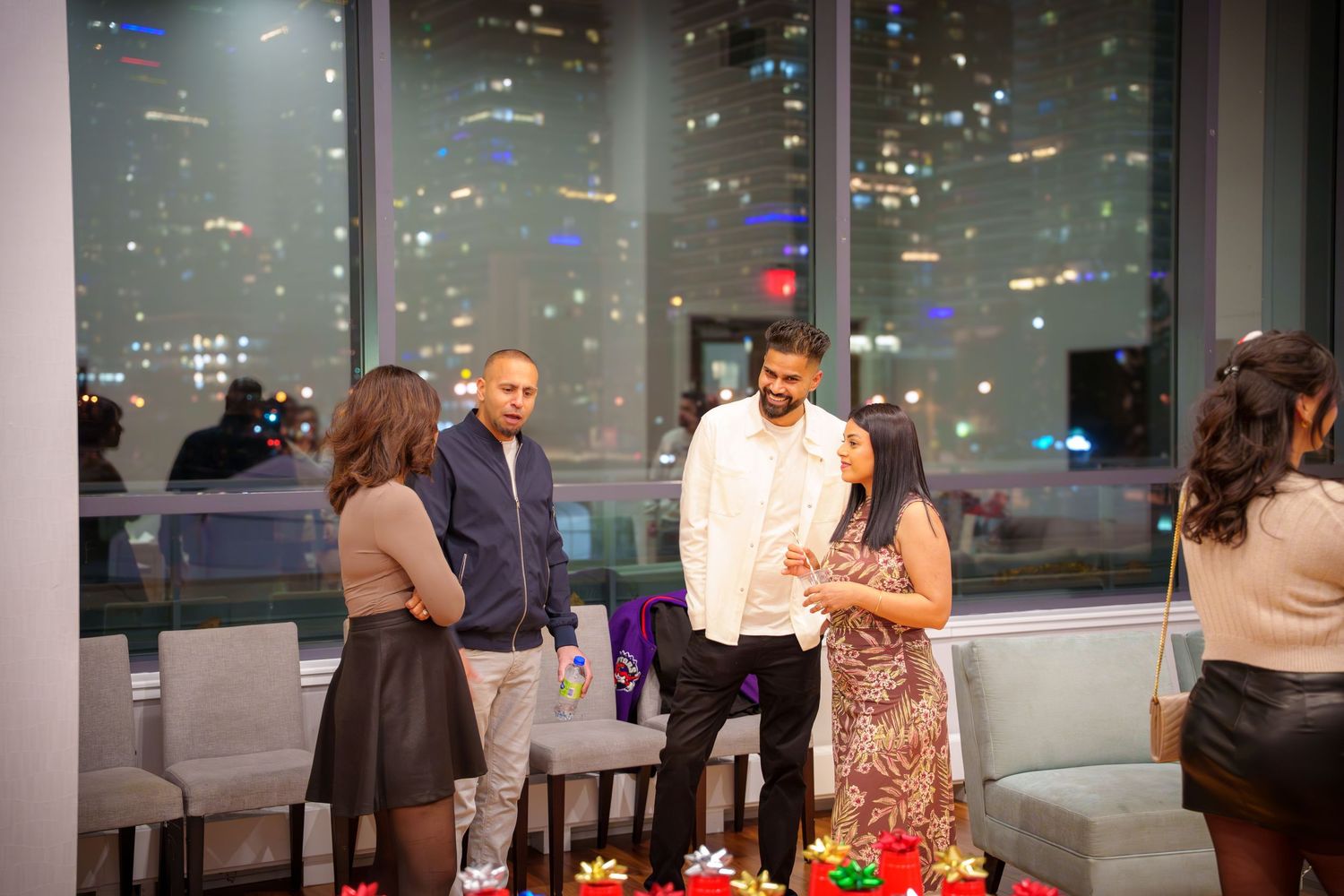 A panoramic view of a modern event space with floor-to-ceiling windows and people mingling at tables.
