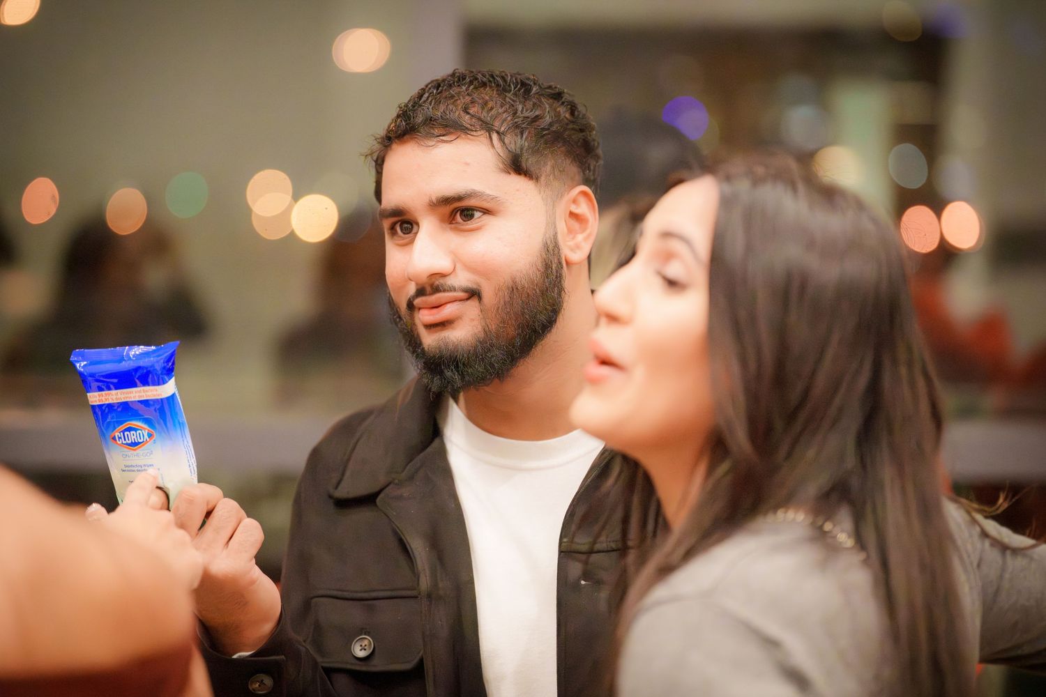 People enjoying drinks and conversation at a social gathering with bokeh lights in background.