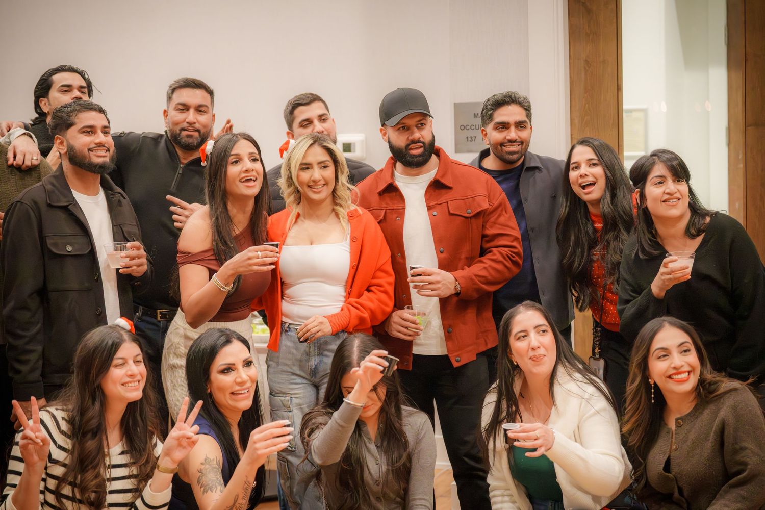 Crowd of people lined up against a wall at a social gathering.