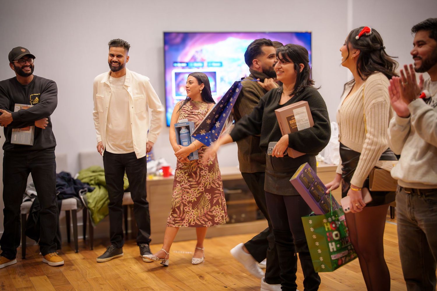 Party guests socialize and dance in front of a colorful display at an indoor event.