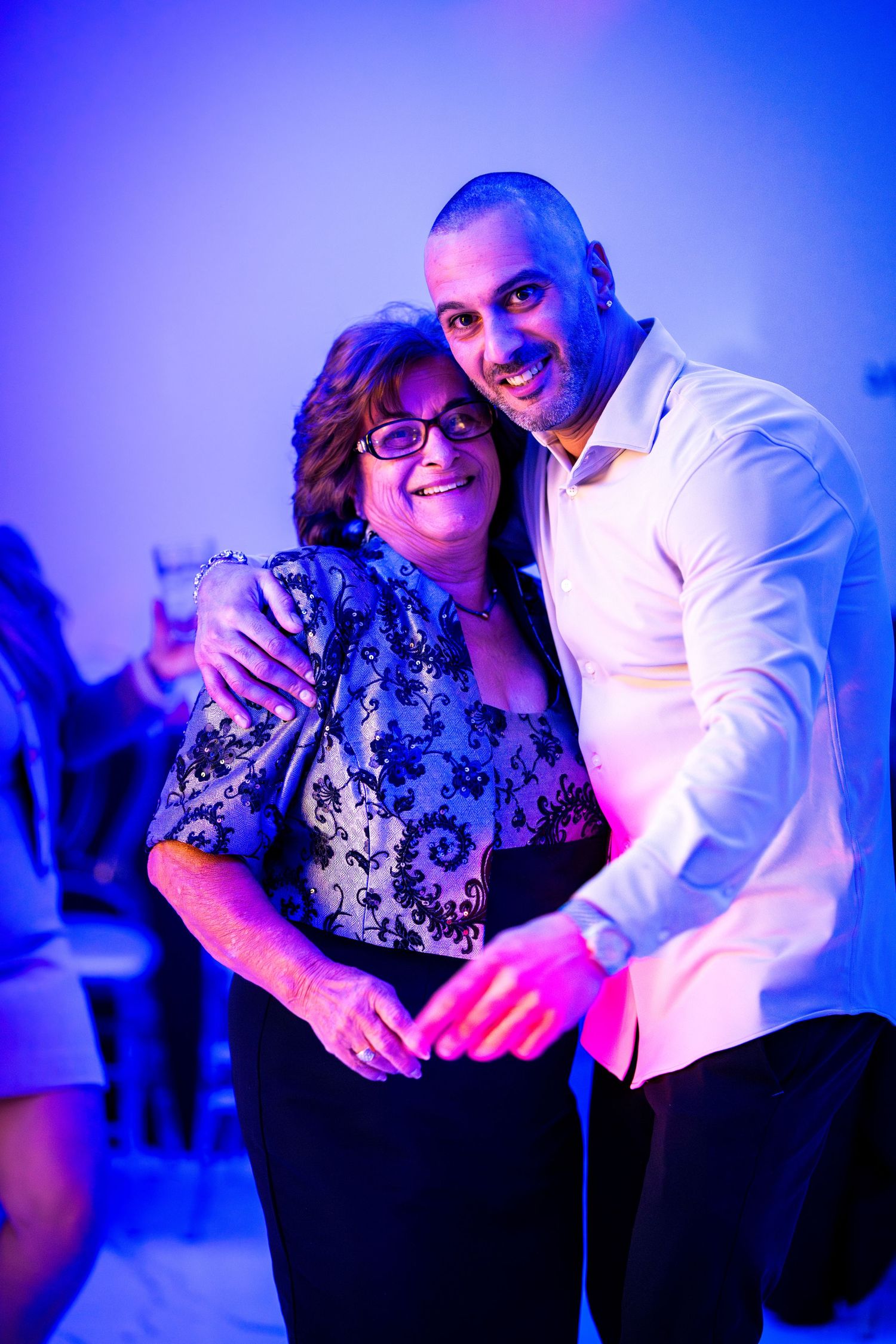 Two people sharing joyful moments together under dramatic blue lighting at an event.