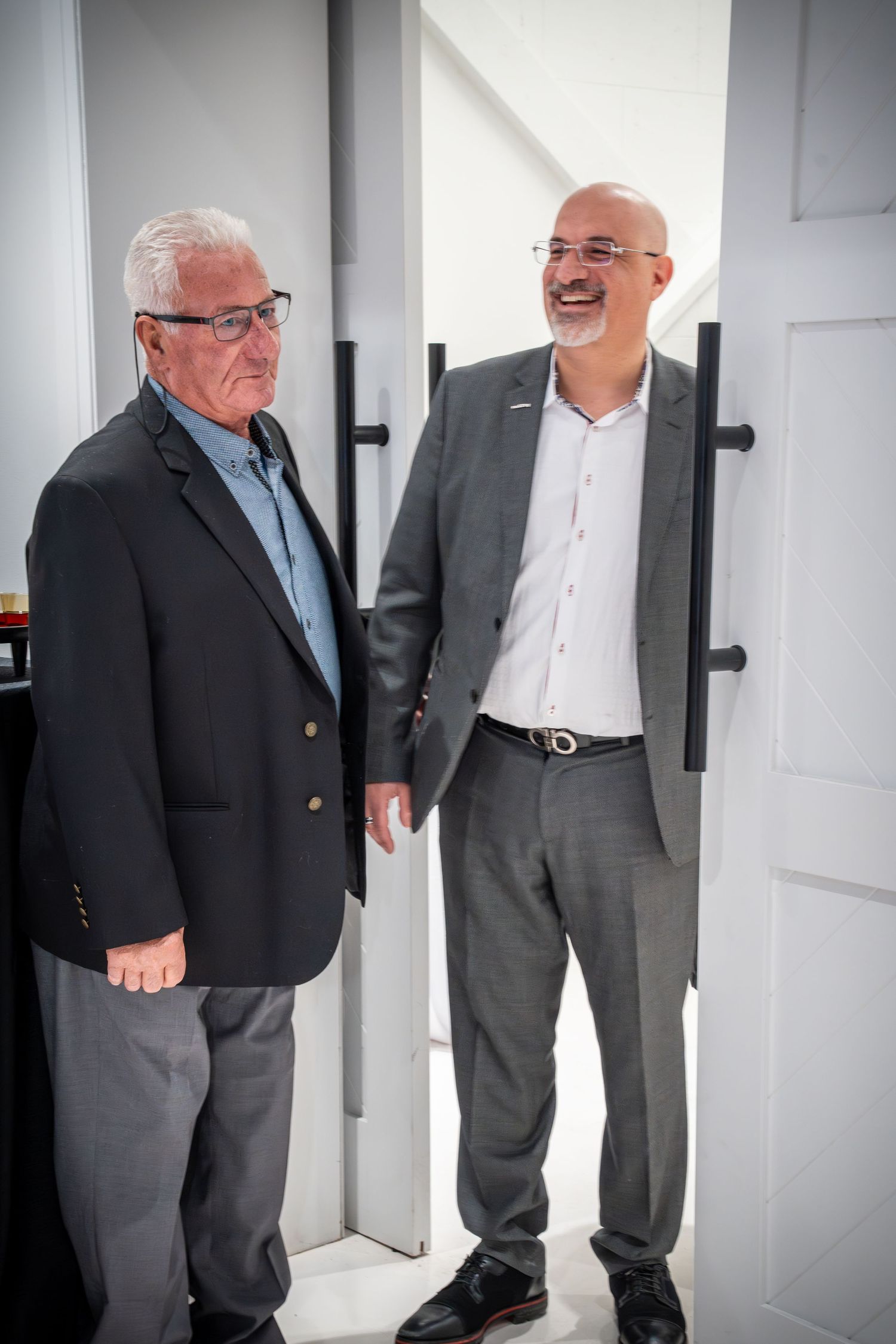 Colleagues sharing a lighthearted moment in a bright office corridor.