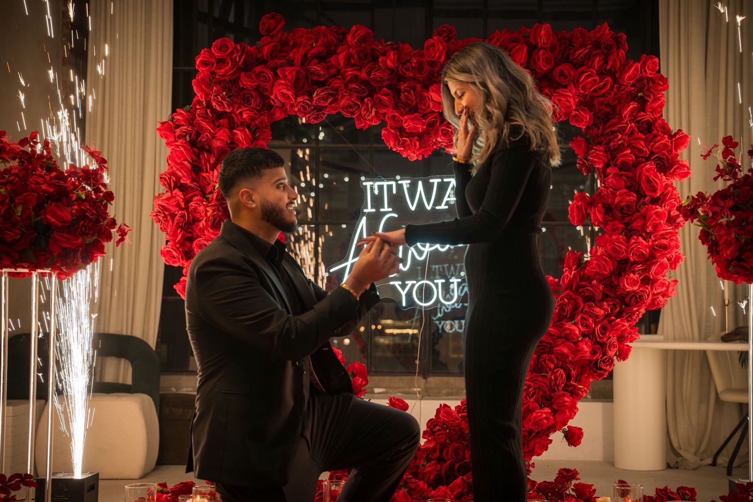 Elegant proposal scene with dramatic red floral backdrop and glowing white candles.