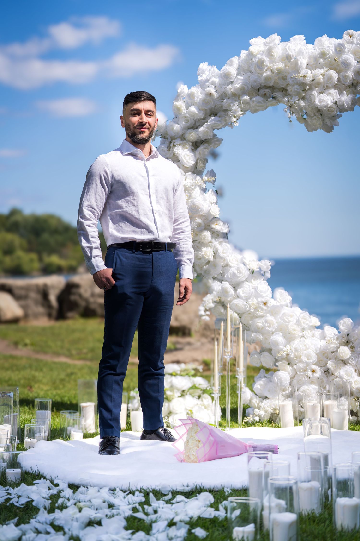 A seaside wedding ceremony site decorated with white balloon arches and glass votive candles.