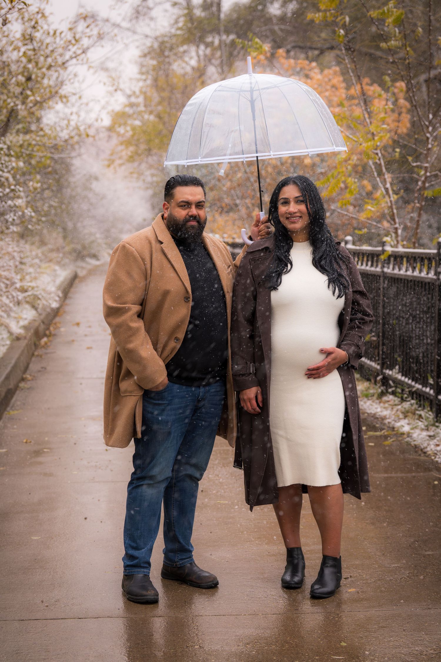 A couple walks together under an umbrella on a rainy autumn path.