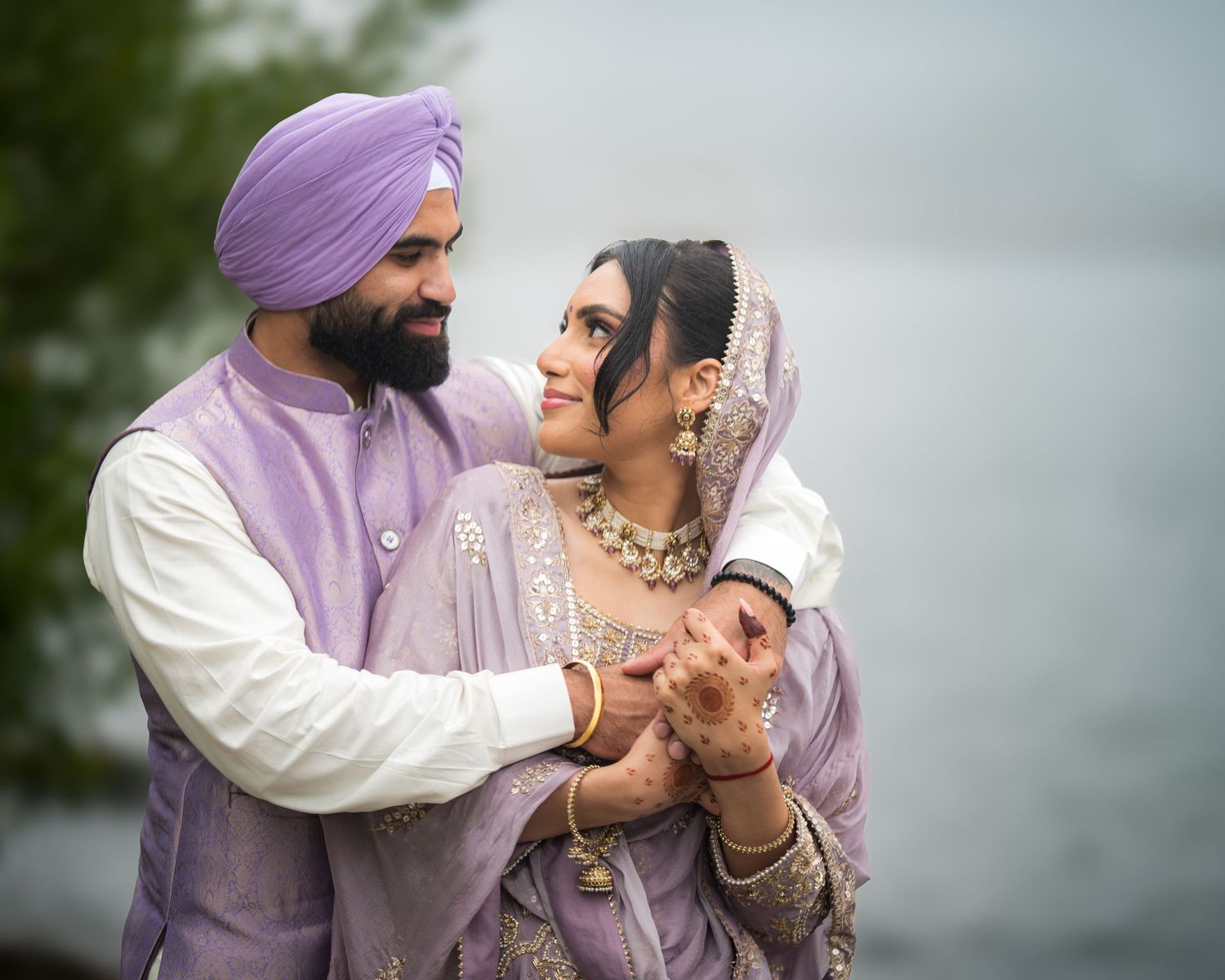 A couple in traditional Indian attire share an intimate moment during their outdoor wedding photoshoot.