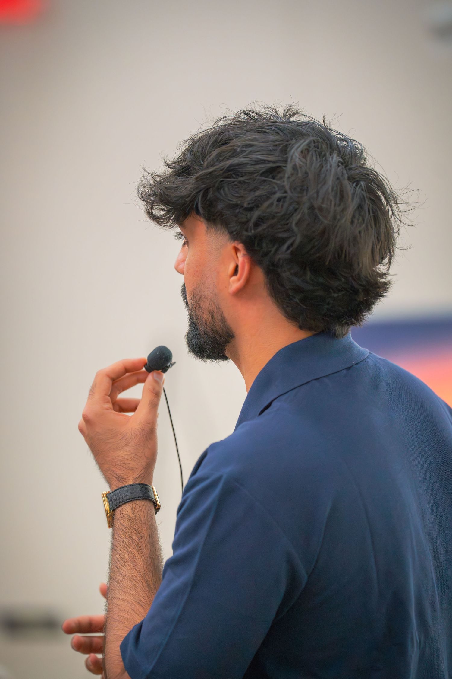 Close-up profile views of someone in a navy blue polo speaking into a microphone during a presentation.