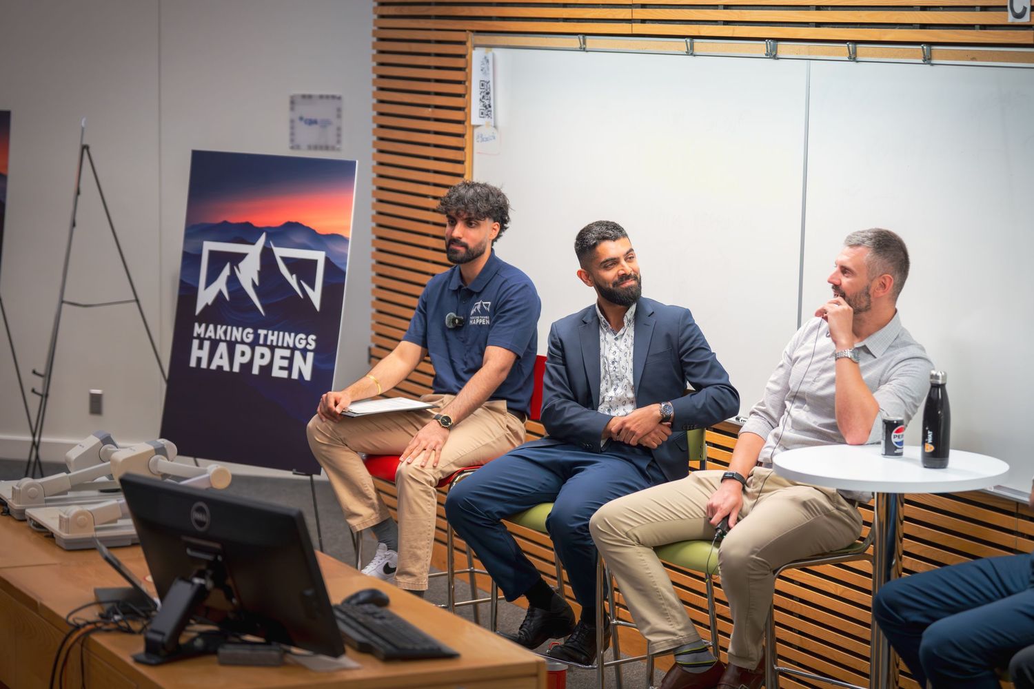 Panel members seated in front of mountain logo backdrop during business presentation.
