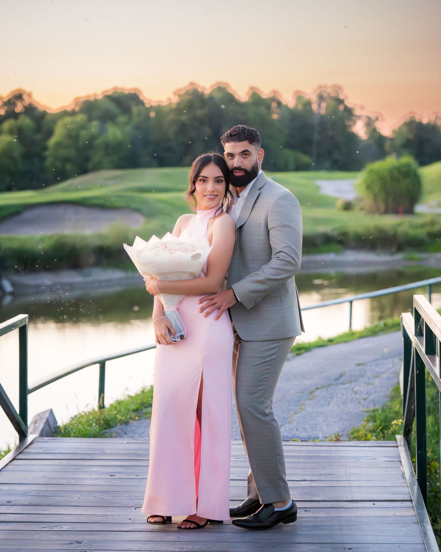 A romantic moment between two people on a wooden boardwalk at sunset.
