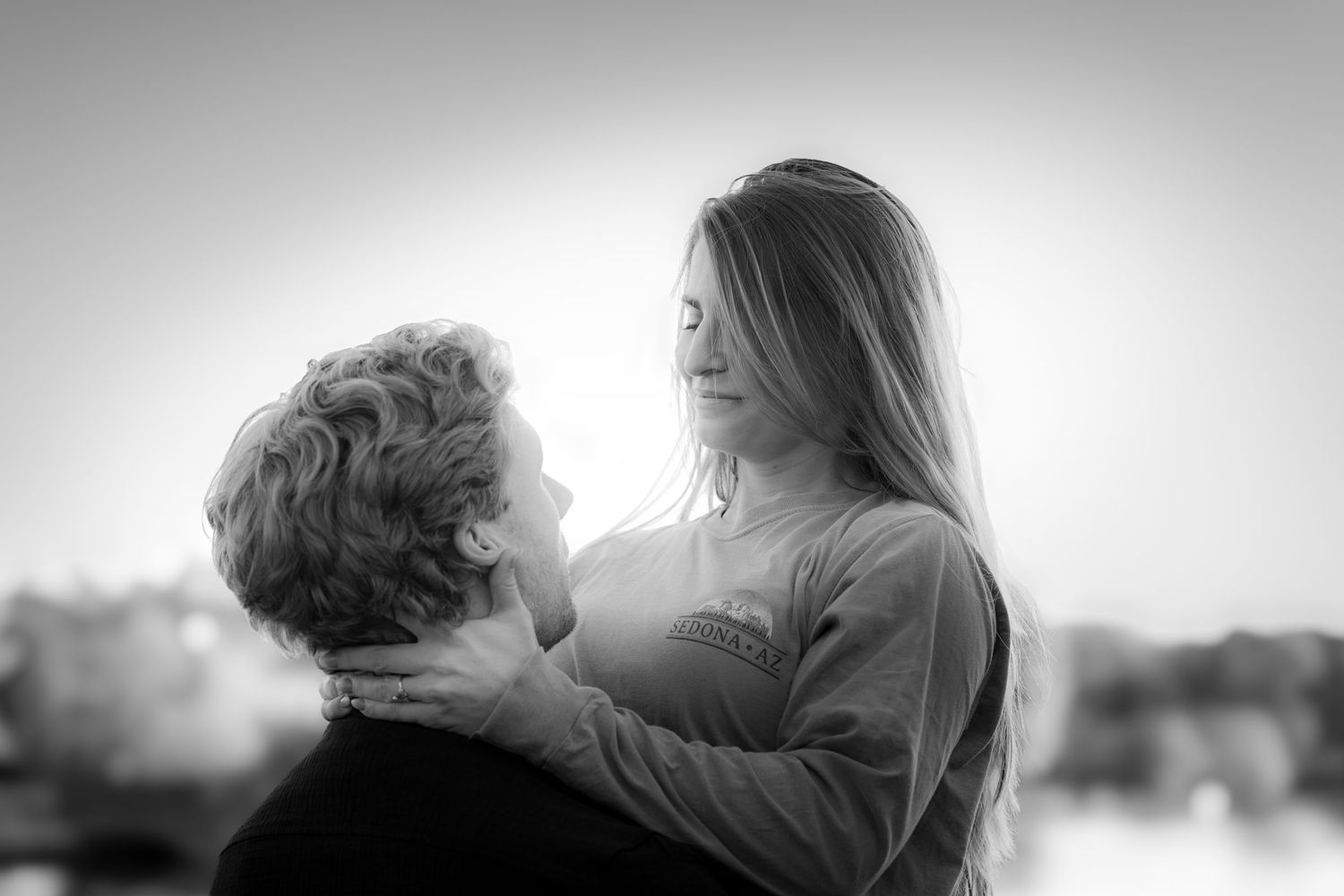 Black and white photo of couple sharing a tender romantic moment outdoors.
