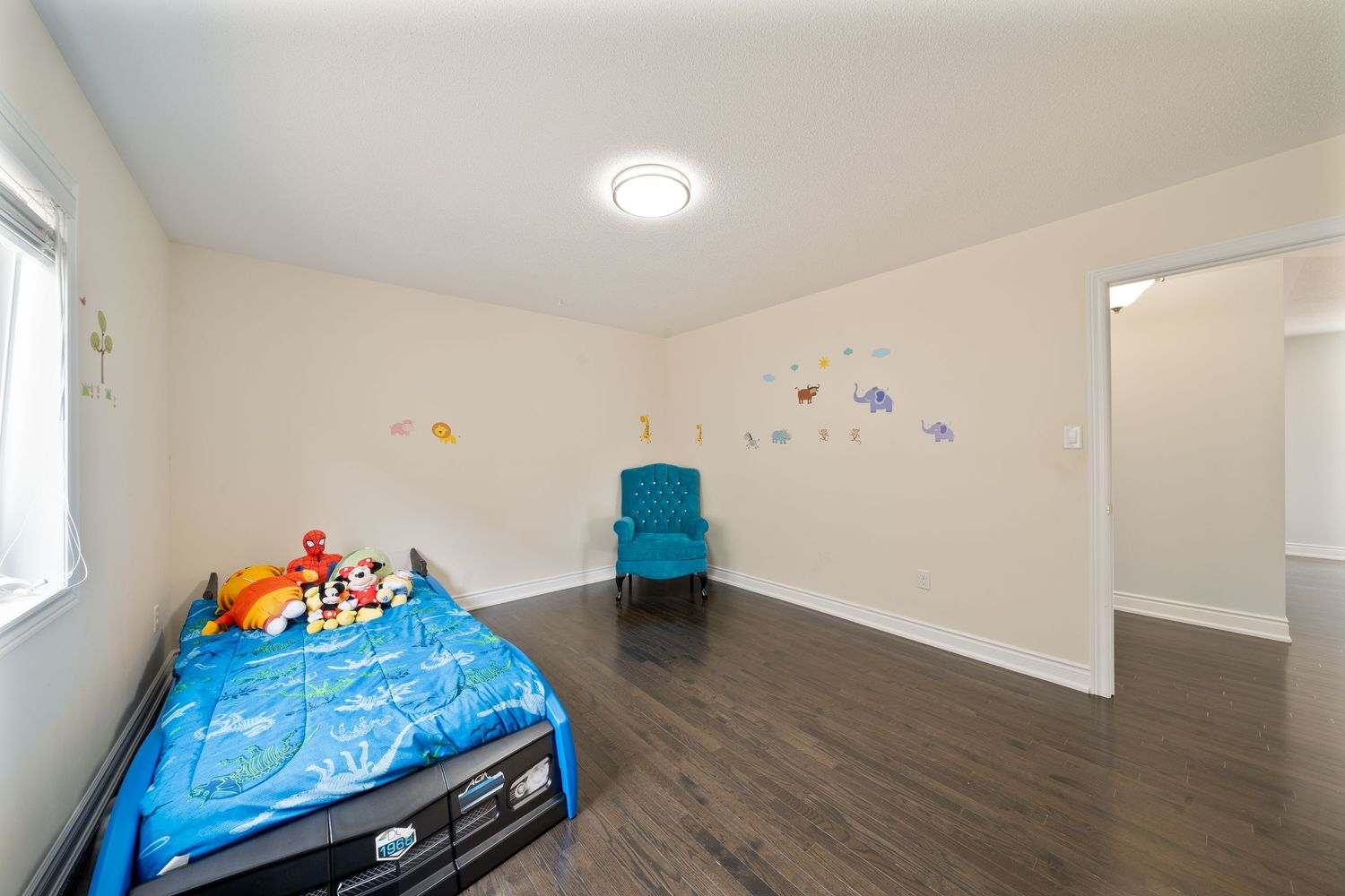 Modern apartment interior with white walls, recessed lighting, and grey hardwood flooring throughout multiple rooms.