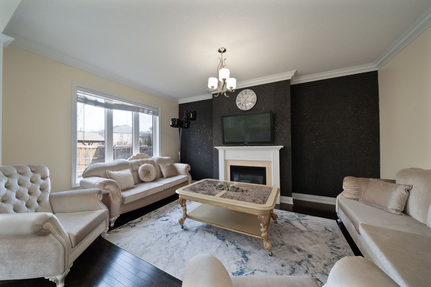 Modern living room interior with white sectional sofa, black accent wall and large windows letting in natural light.